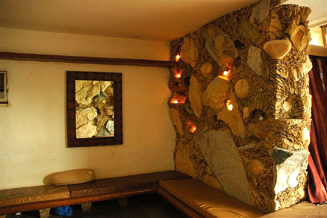Moon Dust Residence - Interior view: leather-upholstered seat cushions, a stone wall, and a mirror reflecting the wall