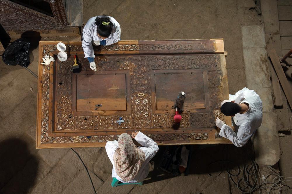 Conservators cleaning a wooden frame from the mausoleum