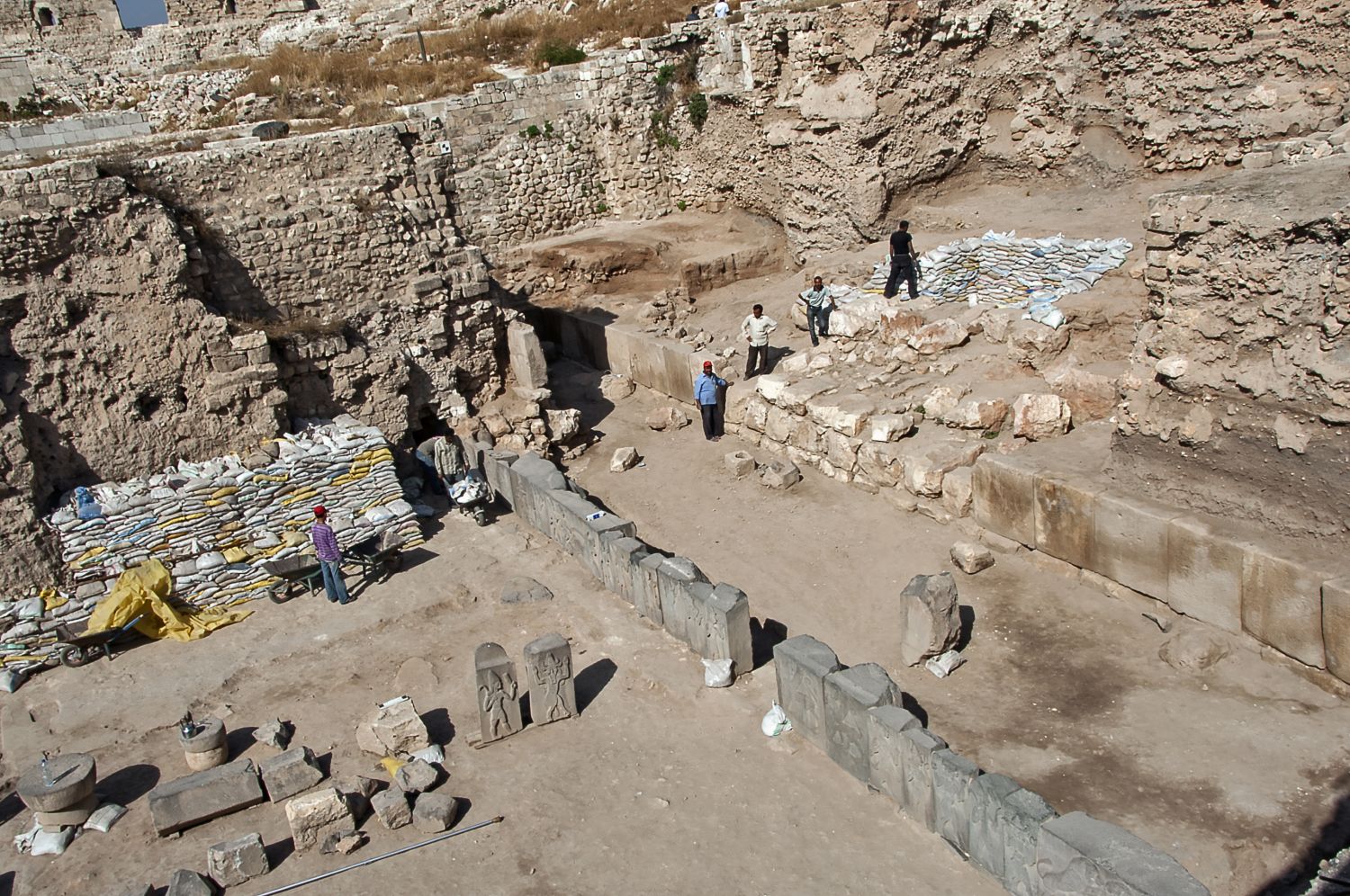General view over excavation facing northwest. Row of panels from platform wall constructed ca. 900 BCE visible in center.