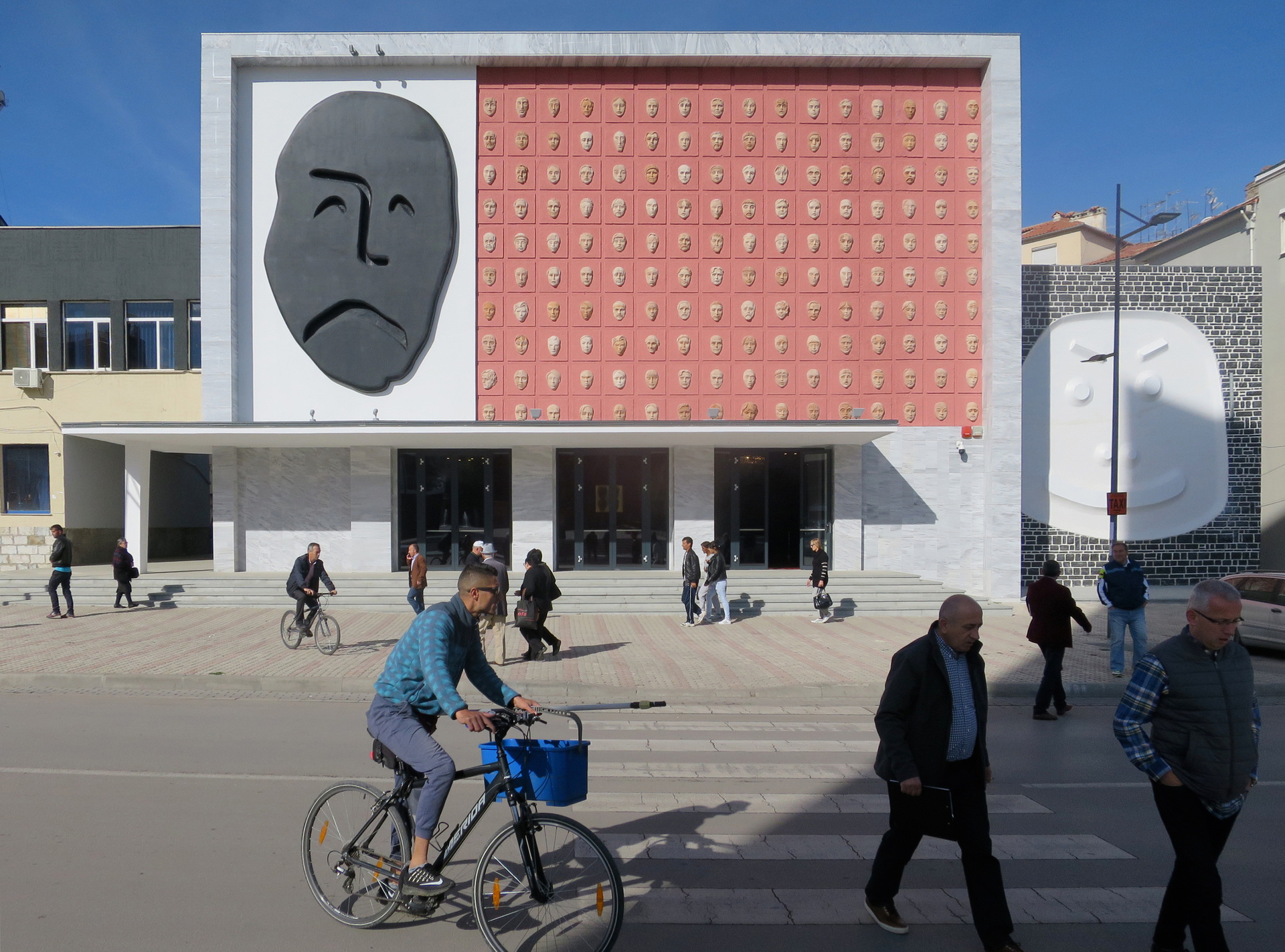 <p>Outside, the traditional theatrical masks of tragedy and comedy are enlarged to sculptural super-signs: tragedy (black, convex) on the main frontage, comedy (white, concave) on the new stair cube.</p>