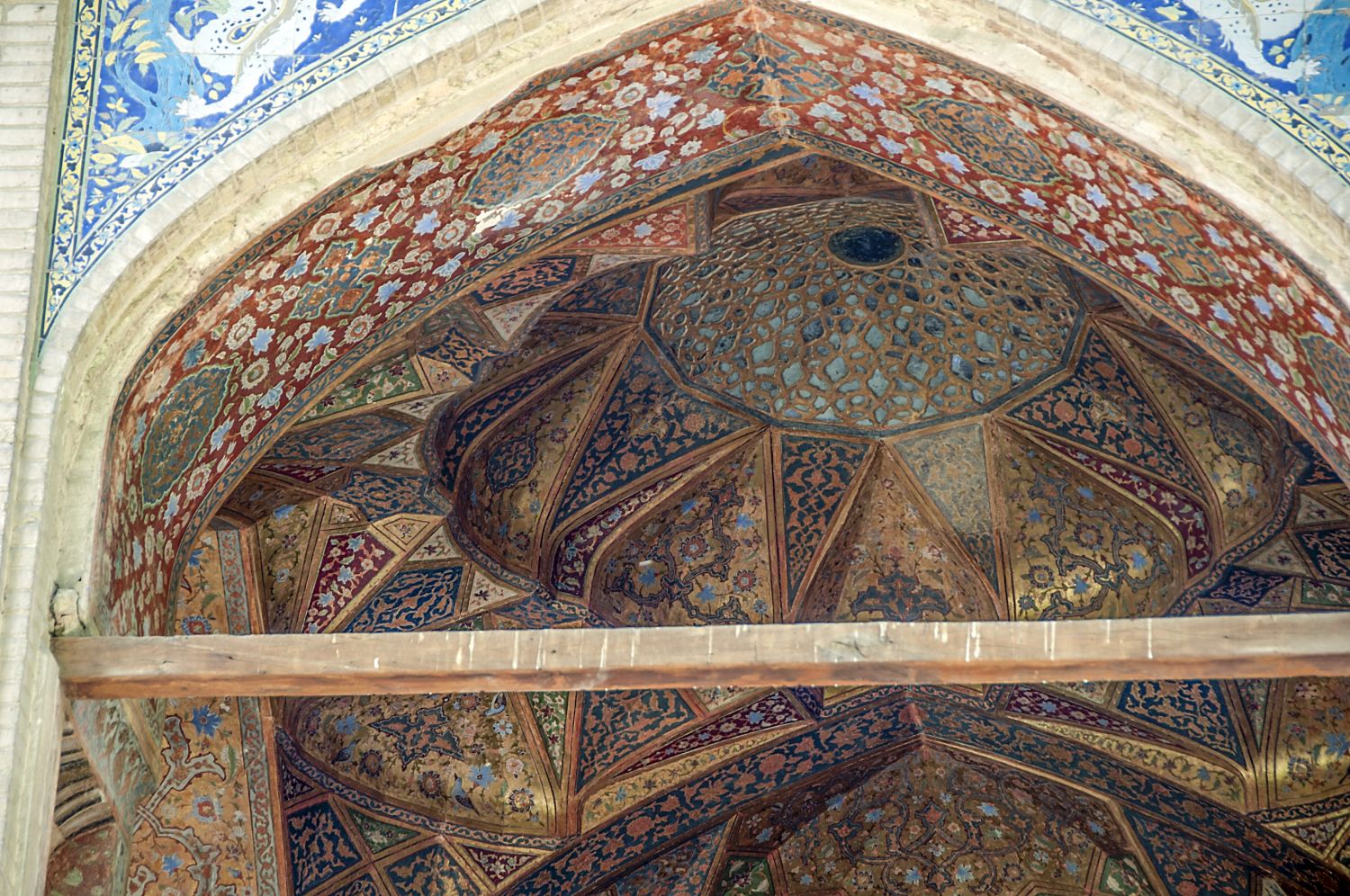 North facade, view into arched opening of a second story gallery flanking the large portico to the west, showing ornately painted muqarnas vault and tile spandrels.