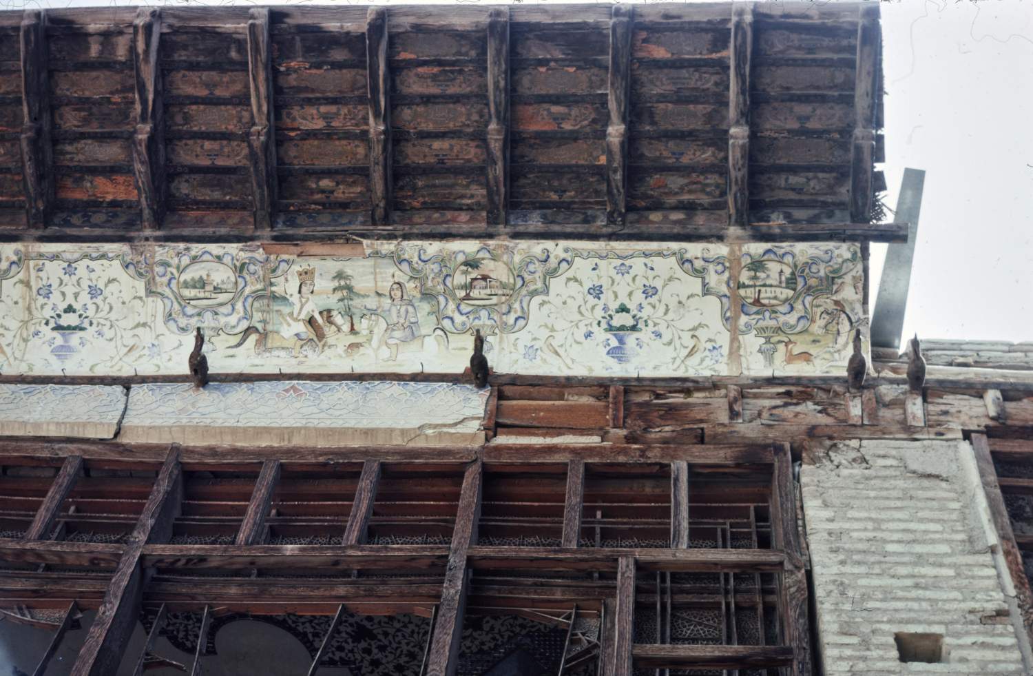 View of wooden awning over windows overlooking courtyard, including painted plaster decorations.