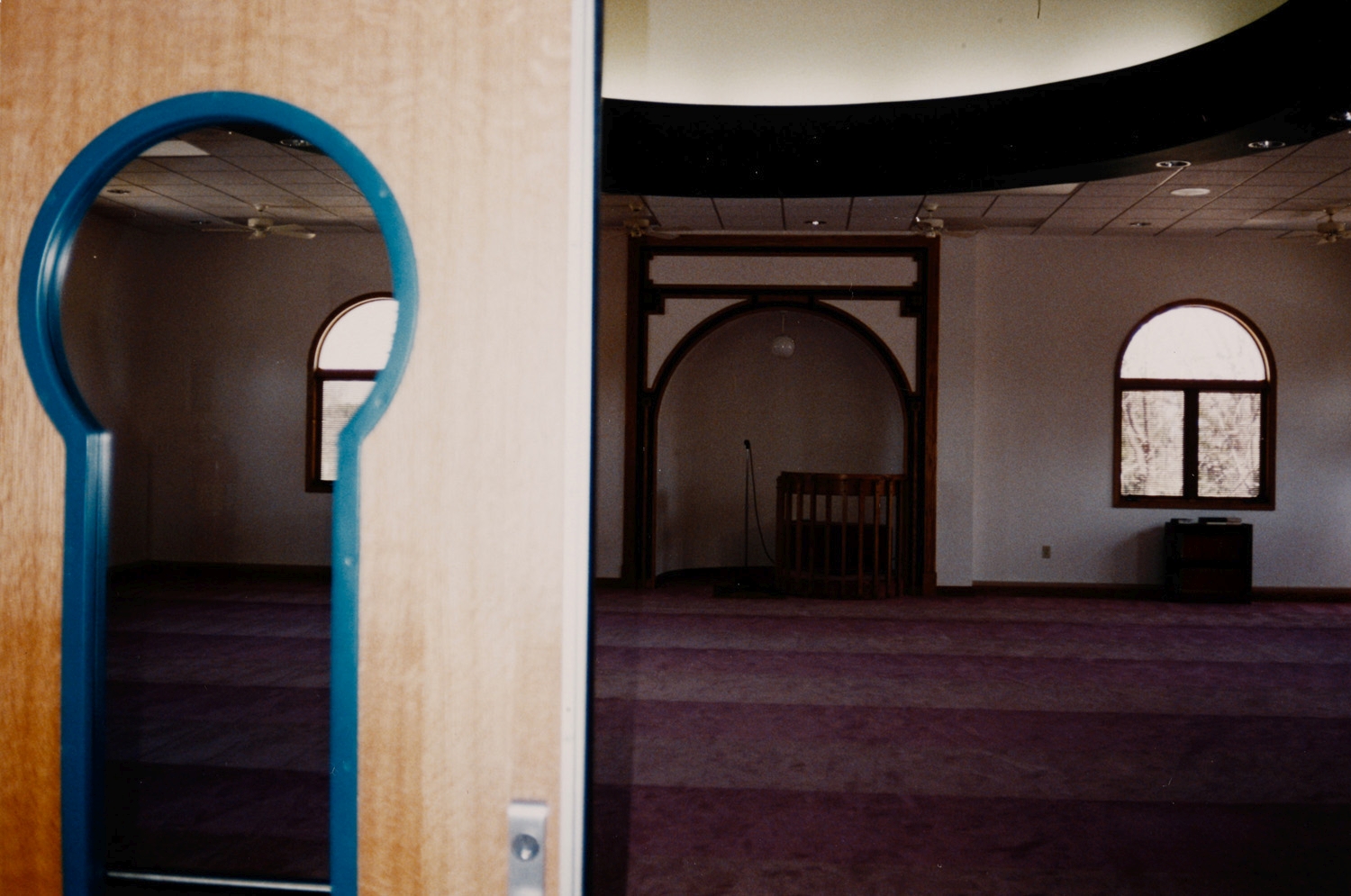 View from prayer hall doorway, with keyhole-shaped window of prayer hall doors, towards mihrab