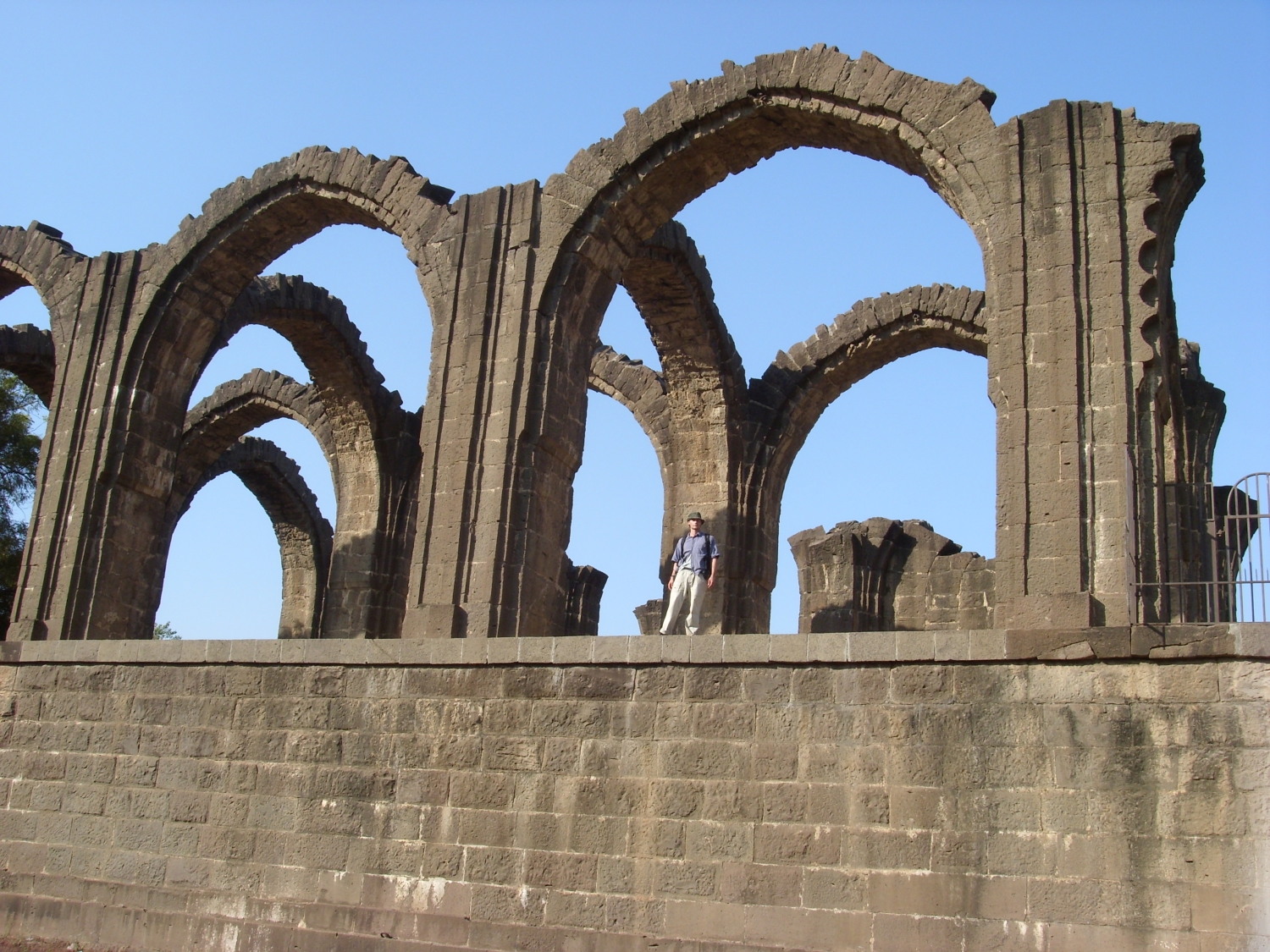 Partial exterior view of arches, showing plinth, with figure for scale