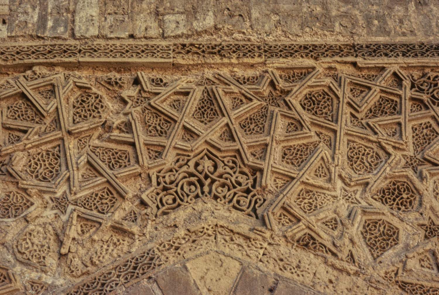 Courtyard: detail view of a spandrel over an archway decorated with a star and polygon pattern carved in terracotta.&nbsp;