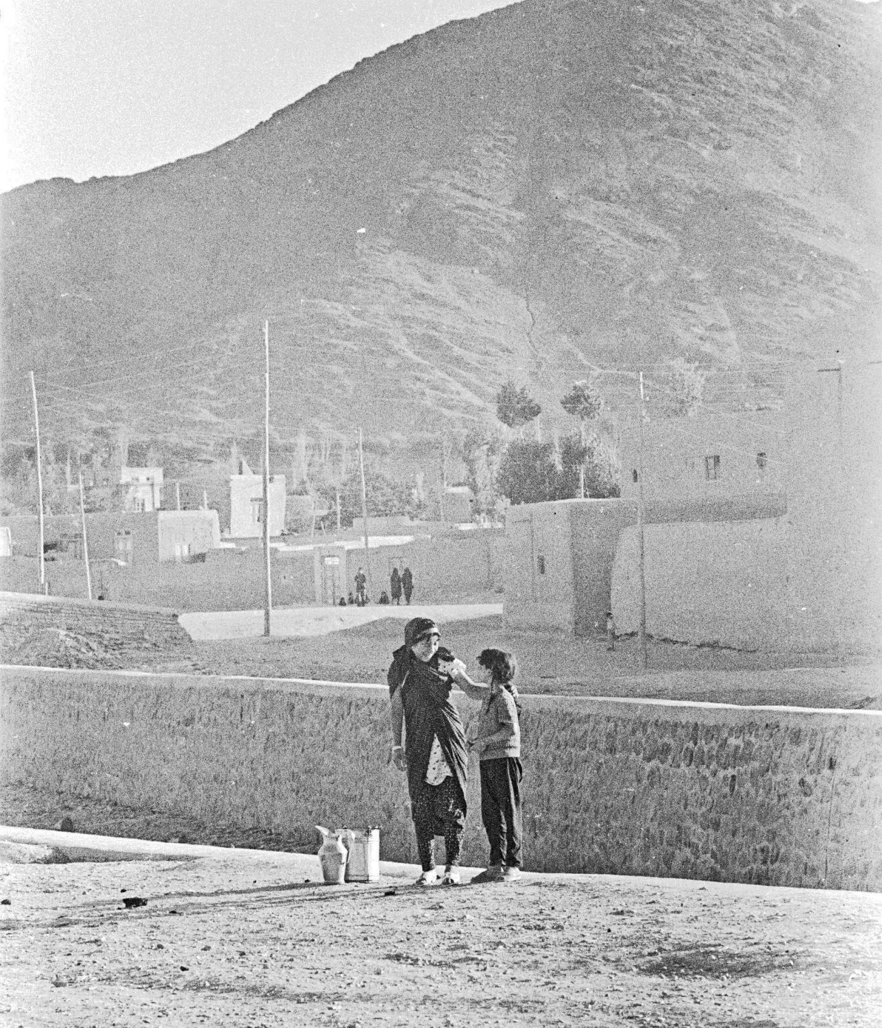 Arak  - View of two young people in Arak, Iran. Village visible in background.