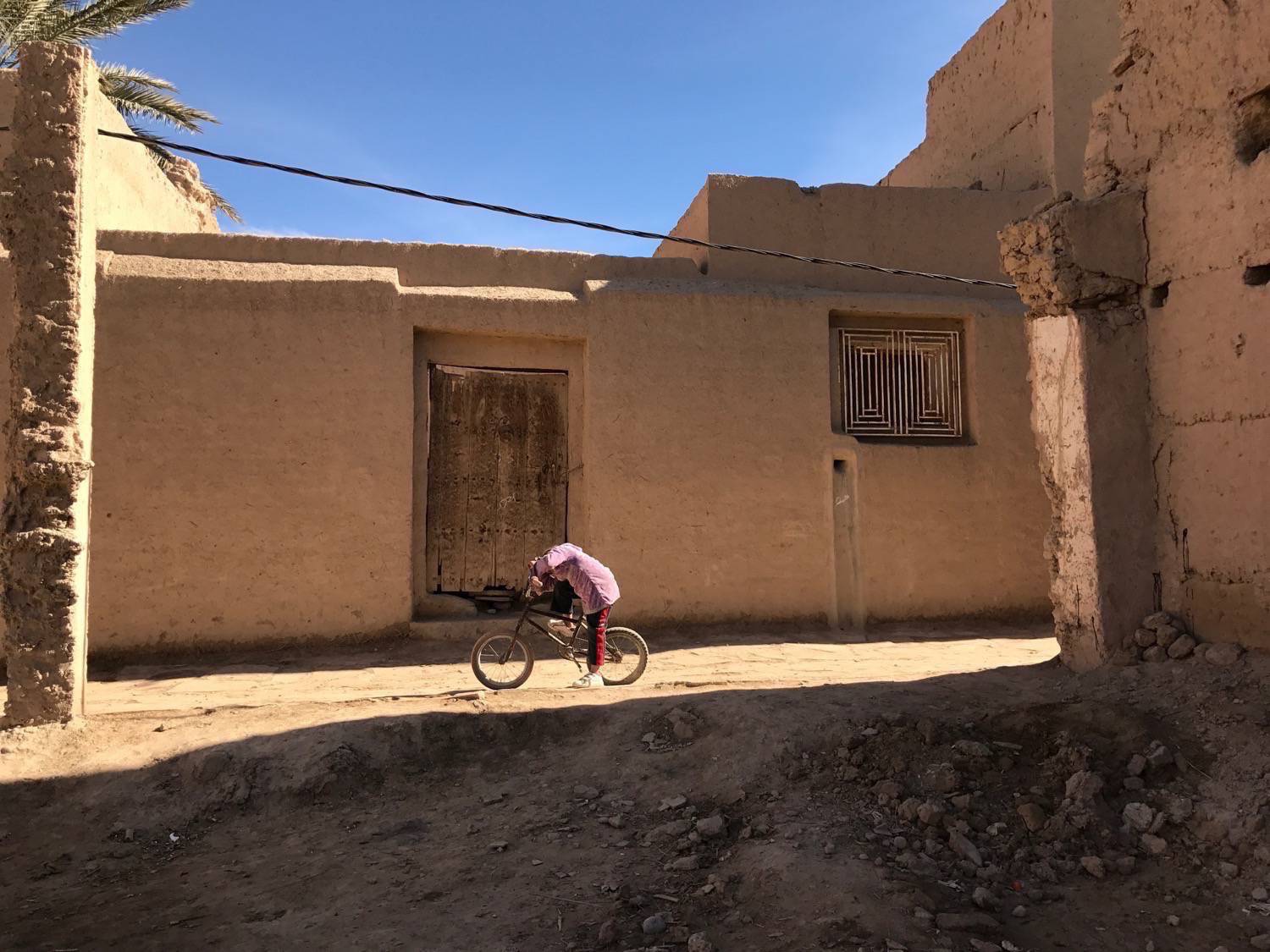 Ksar Rissani - Young girl on her bike heading to a school in an area outside the walls of the Ksar 