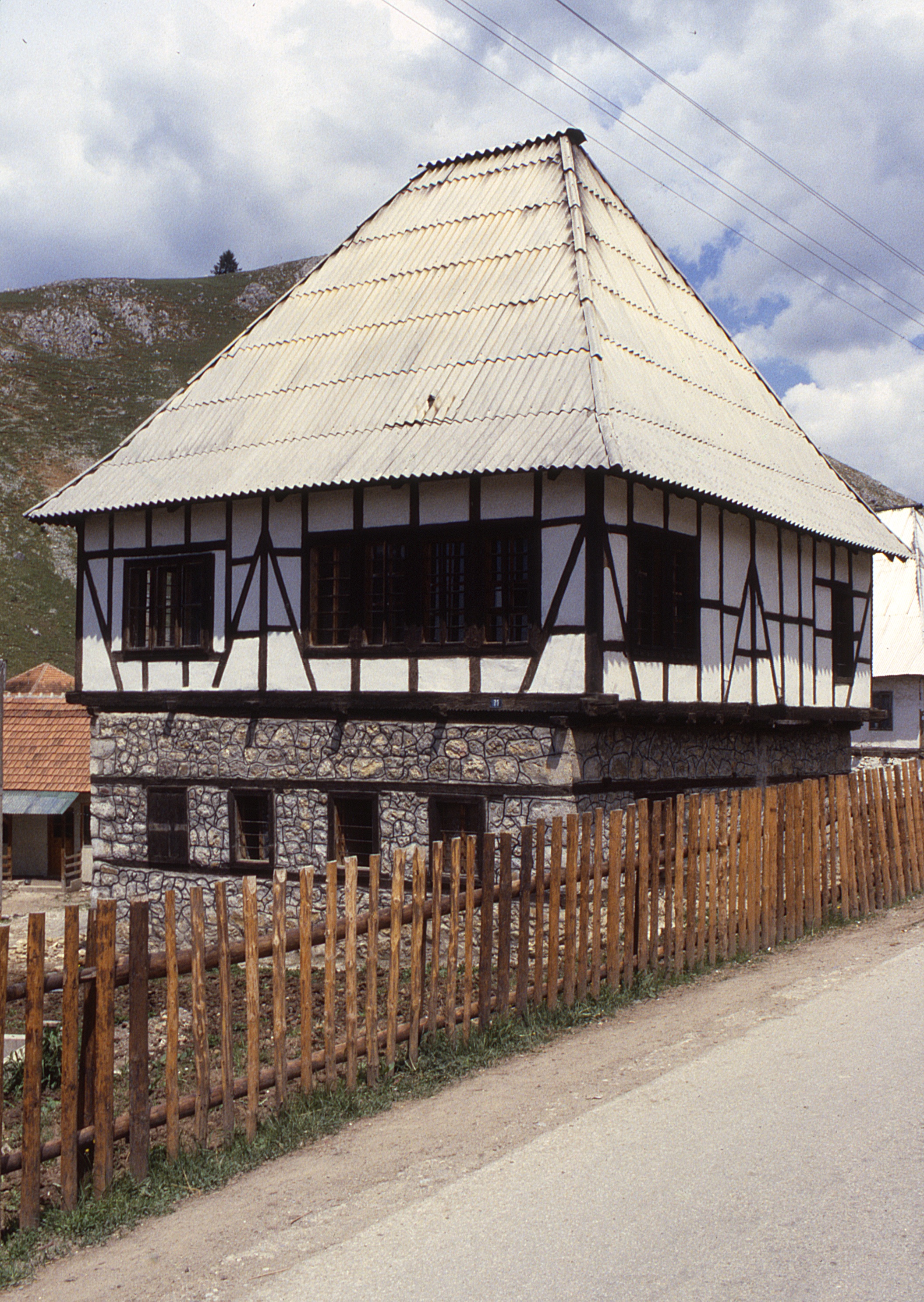 <p>The kuća has a large number of windows on these facades visible from the road. The wooden reinforcing strips are continuous and provide support over the windows in the stone walls. The wooden reinforcing strips are normally created by setting face members on the interior and exterior surfaces that are connected by cross members mortised into the face members; this allows masonry work to interlock with the strips. The diagonal timber bracing in the upper walls stabilize the corners and allow large openings in these walls.</p>