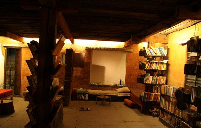 Detail of sleeper wood roof, plastering, diffused lighting, and book stack