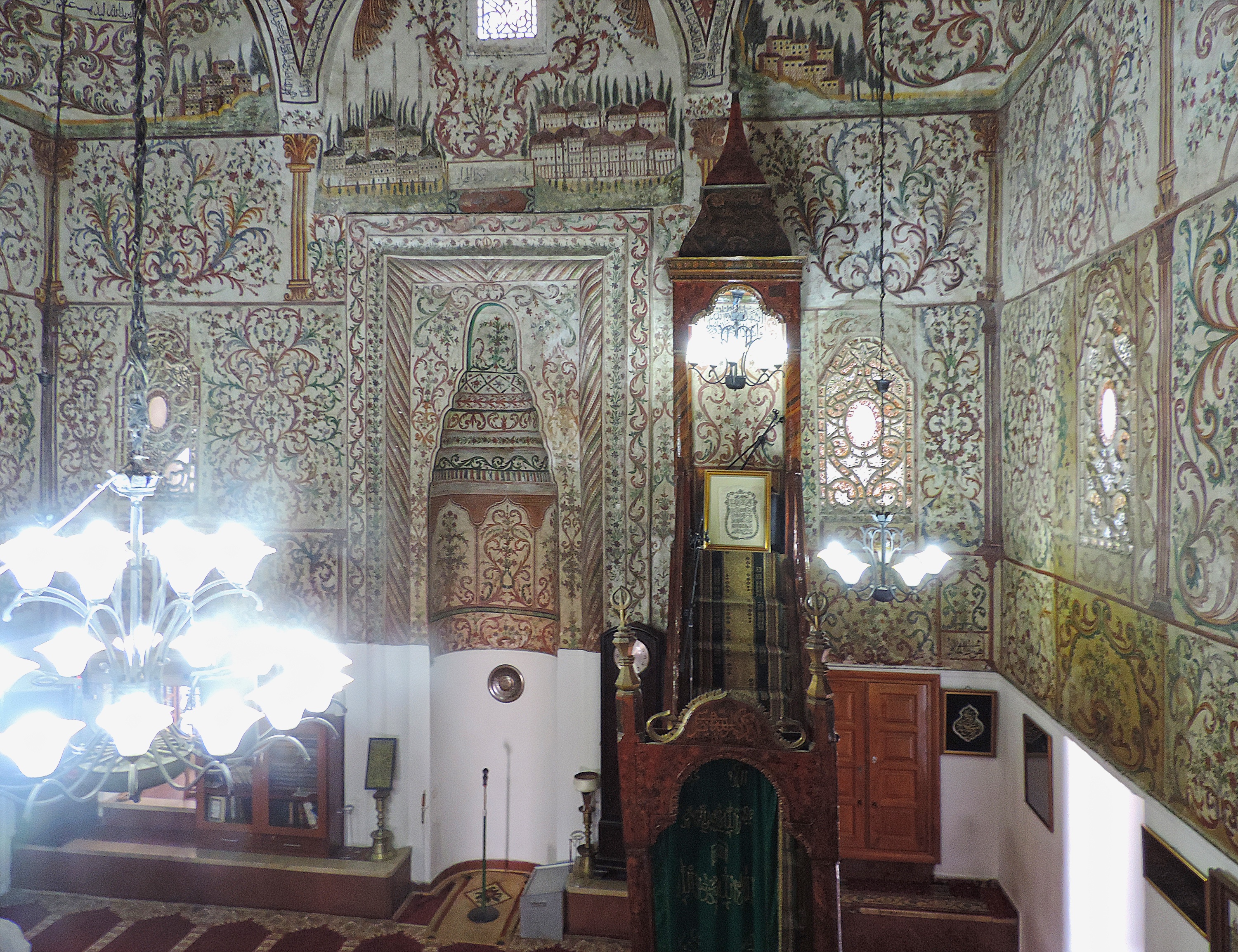 <p>The mosque prayer hall interior is decorated with painted panels of intricate plant motifs and architectural scenes, which cover the upper walls and domed ceiling, viewed here from the balcony. The mosque is designated a Cultural Monument of Albania.</p>