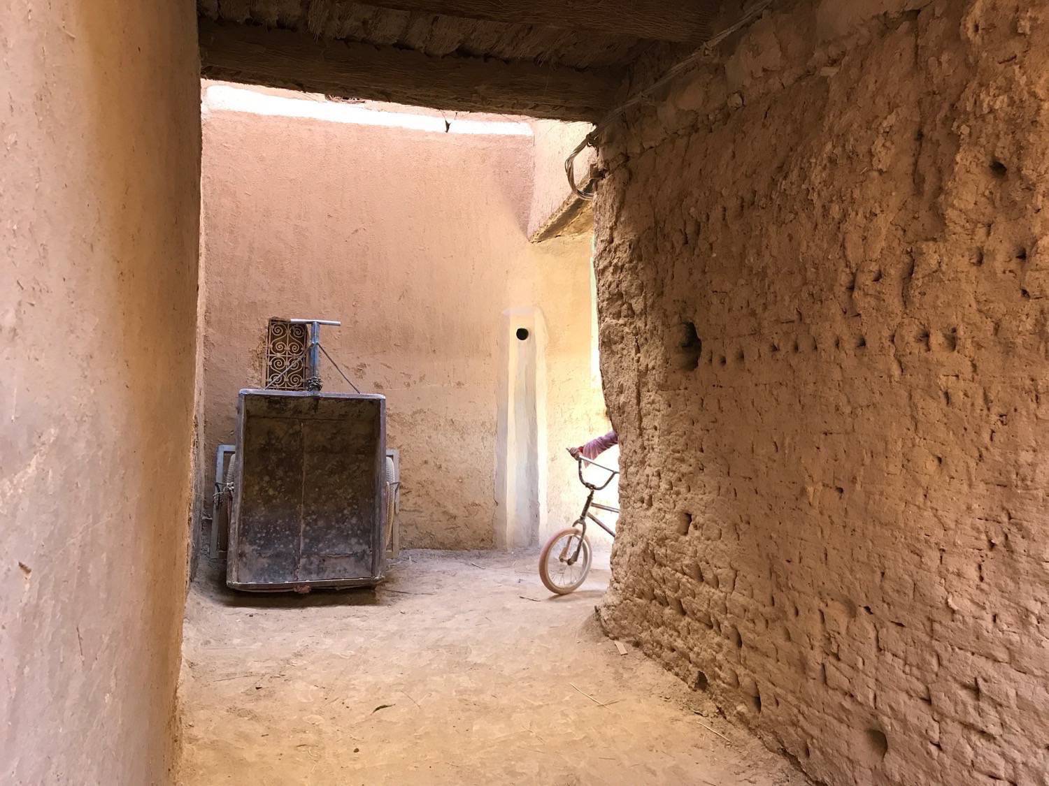 Ksar Rissani - A corner alleyway  showing a wheeled cart used to bring in heavy items into the Ksar.  This section shows some of the different construction finishes as well as some exposed palm wood on the ceiling  