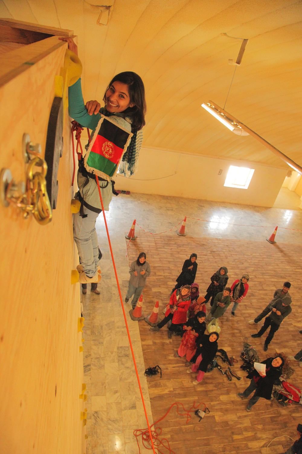 Education Coordinator Benafsha celebrates being the first Afghan woman to climb the 3-faced, 9 metre high climbing wall at Skateistan