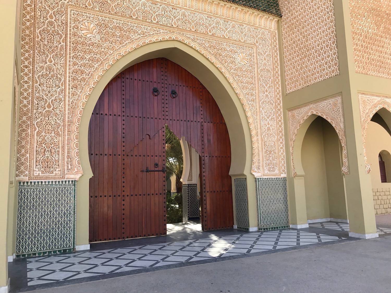 The main entrance featuring an imposing wooden gate and a carved archway  leading to the Moulay Ali Cherif mausoleum complex