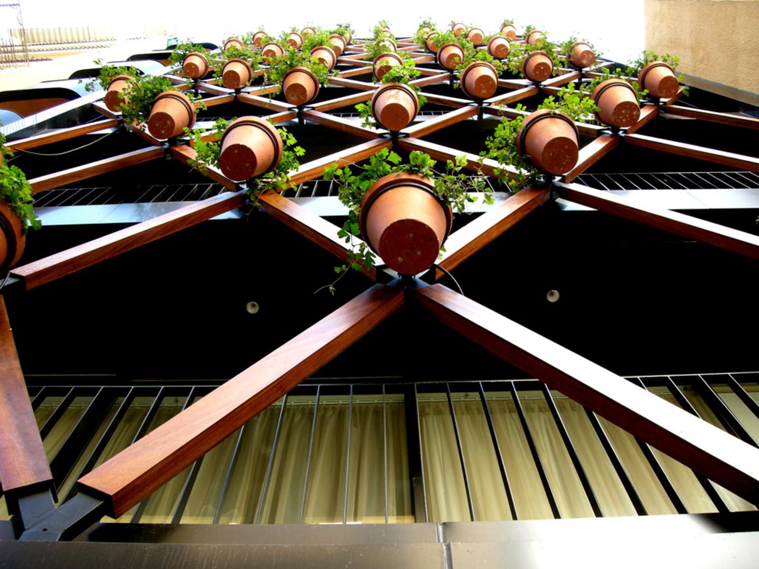Looking up at the structure of interlocking wooden elements with suspended clay pots