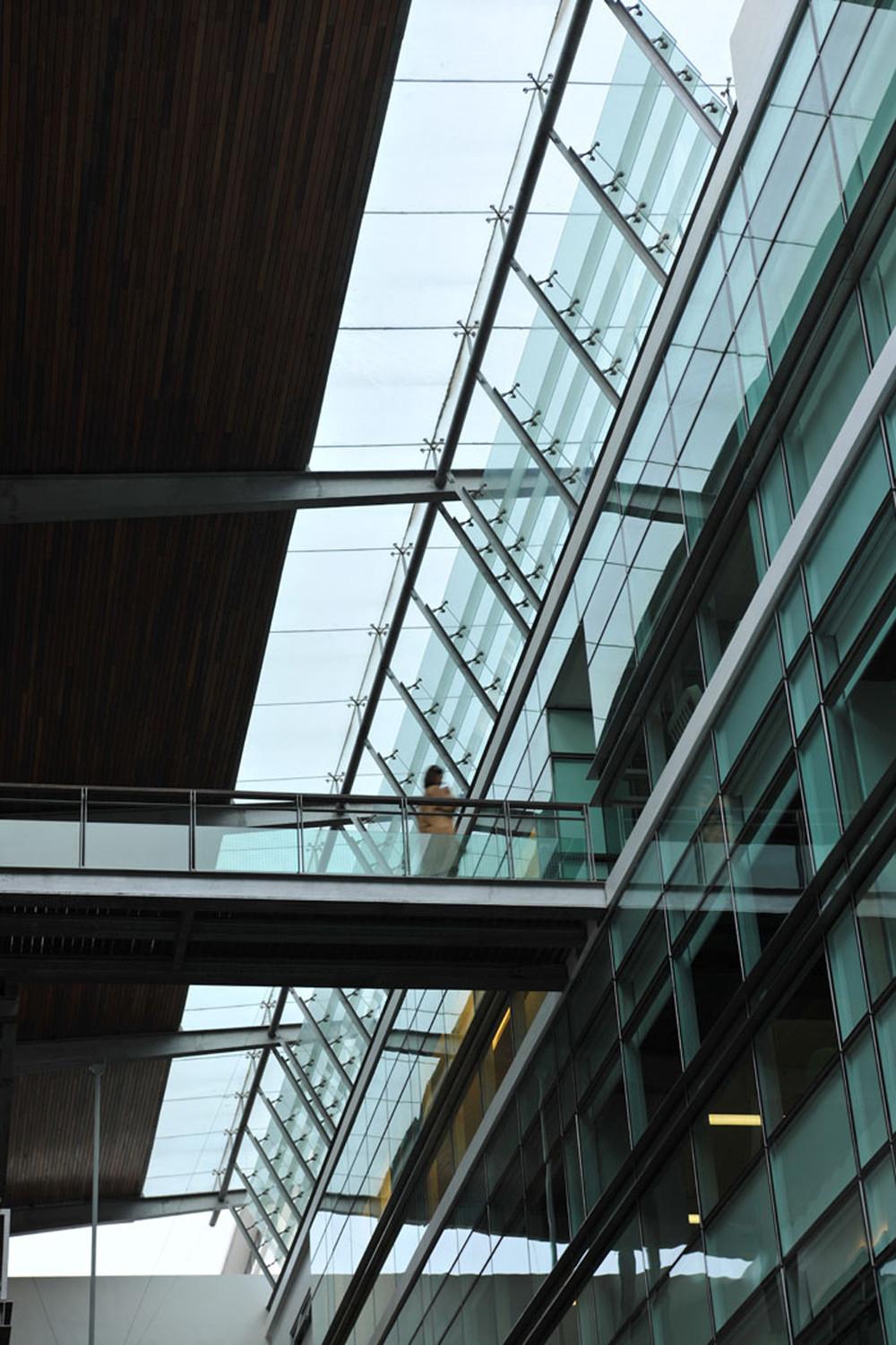 Bridges flying across the soaring void of the atrium. A steel and timber roof canopy over-sails the class louvered clerestory that serves as a rain-screen and ventilating device for the shelter atrium