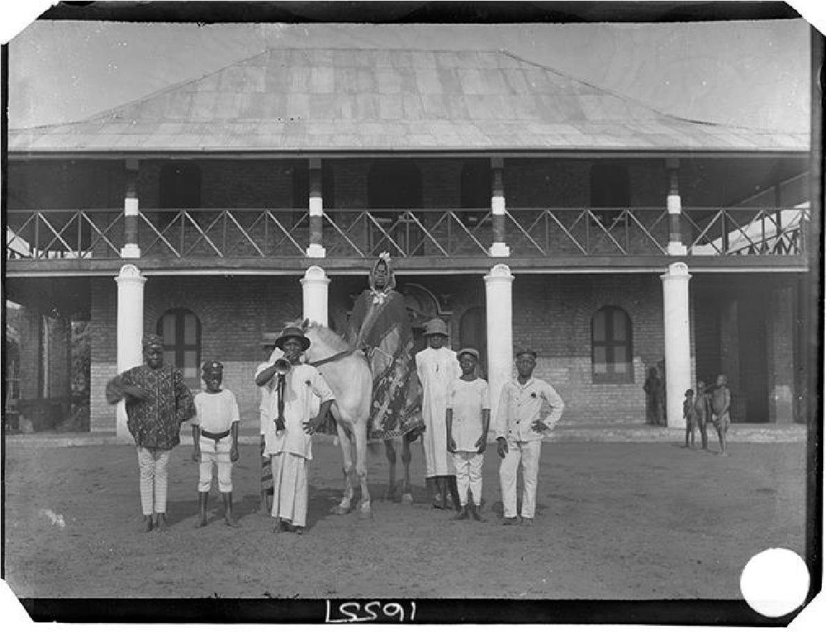Egedege N’okaro - Chief Iyamu with retainers photographed in front of Egedege N’okaro. Benin City, 1909. Photograph by N.W. Thomas. NWT 1361. RAI 400.16557.