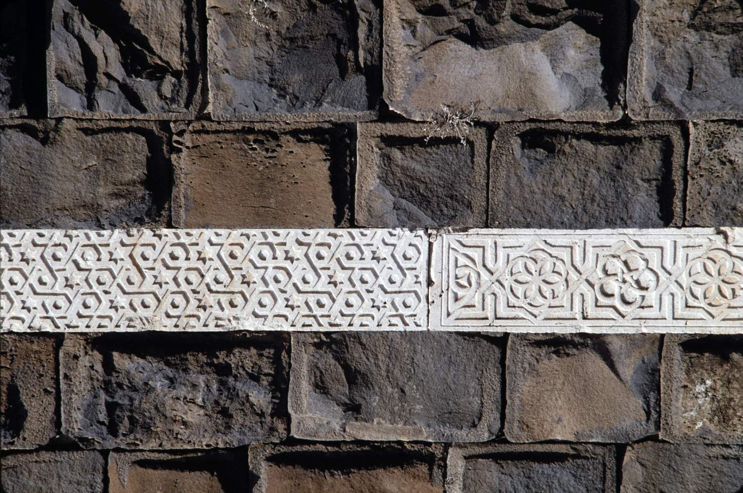 Band of geometric ornament on walls showing two different patterns, one based on six-point stars and hexagons, and another on eight-point stars and rosettes.