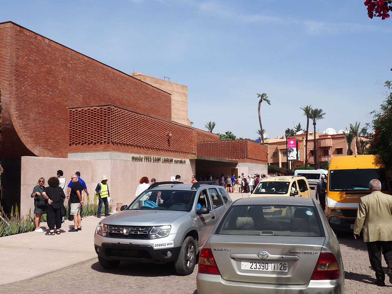 Pedestrians and vehicles on the sidewalk and street of the entrance facade<br>