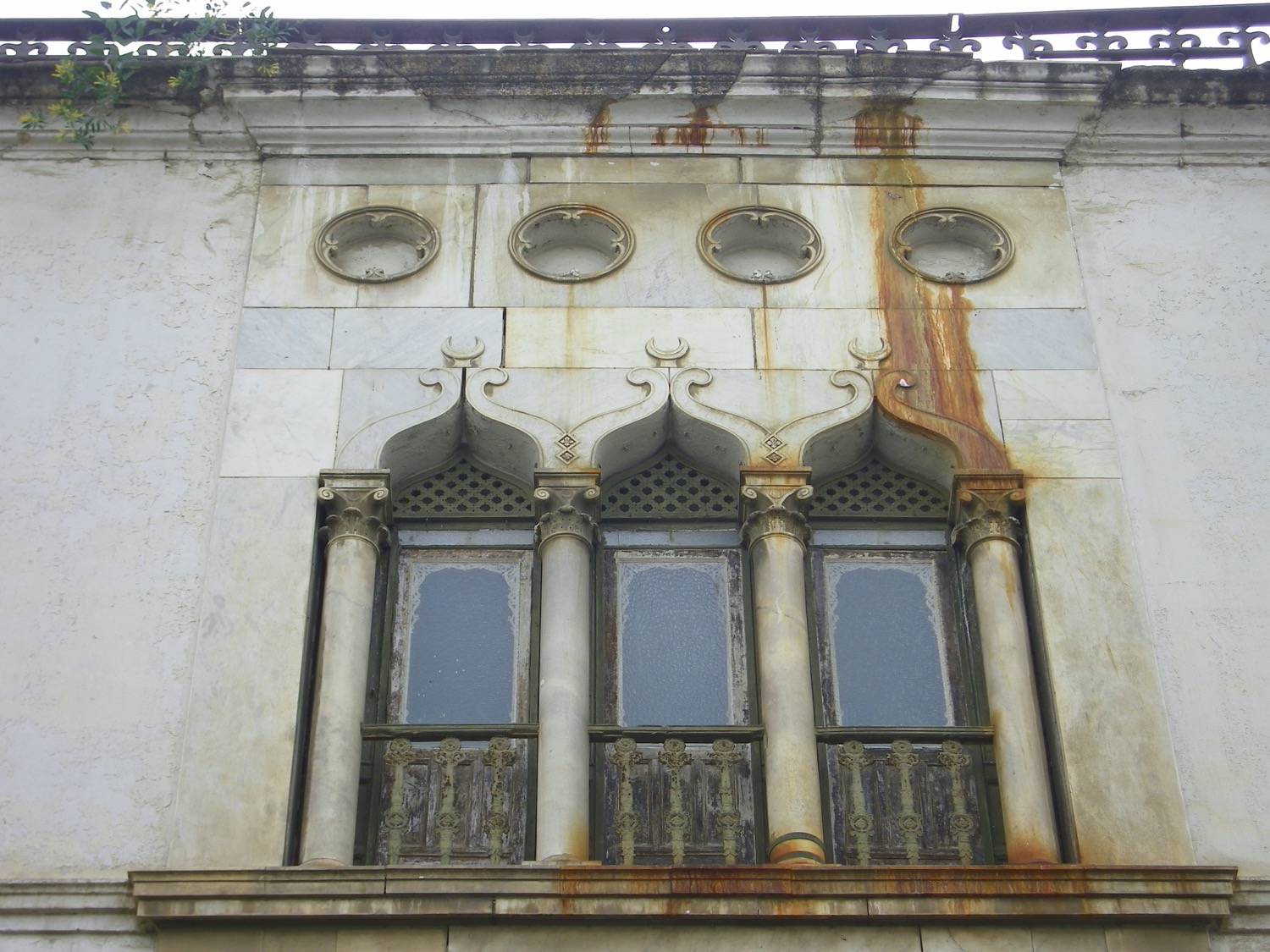 Exterior view of a tripartite window with a balconet and four circular windows above