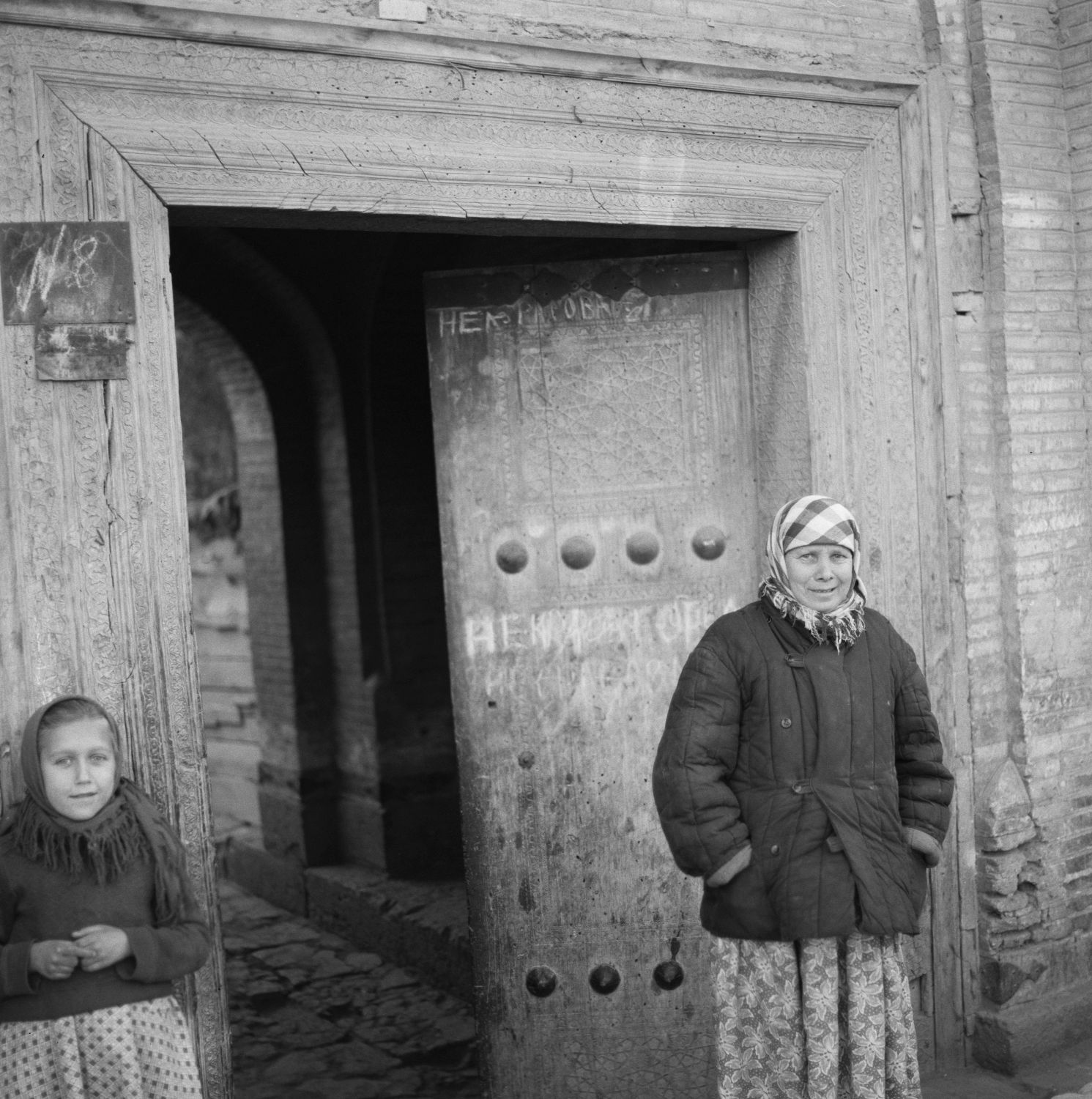A woman and a girl standing next to door.