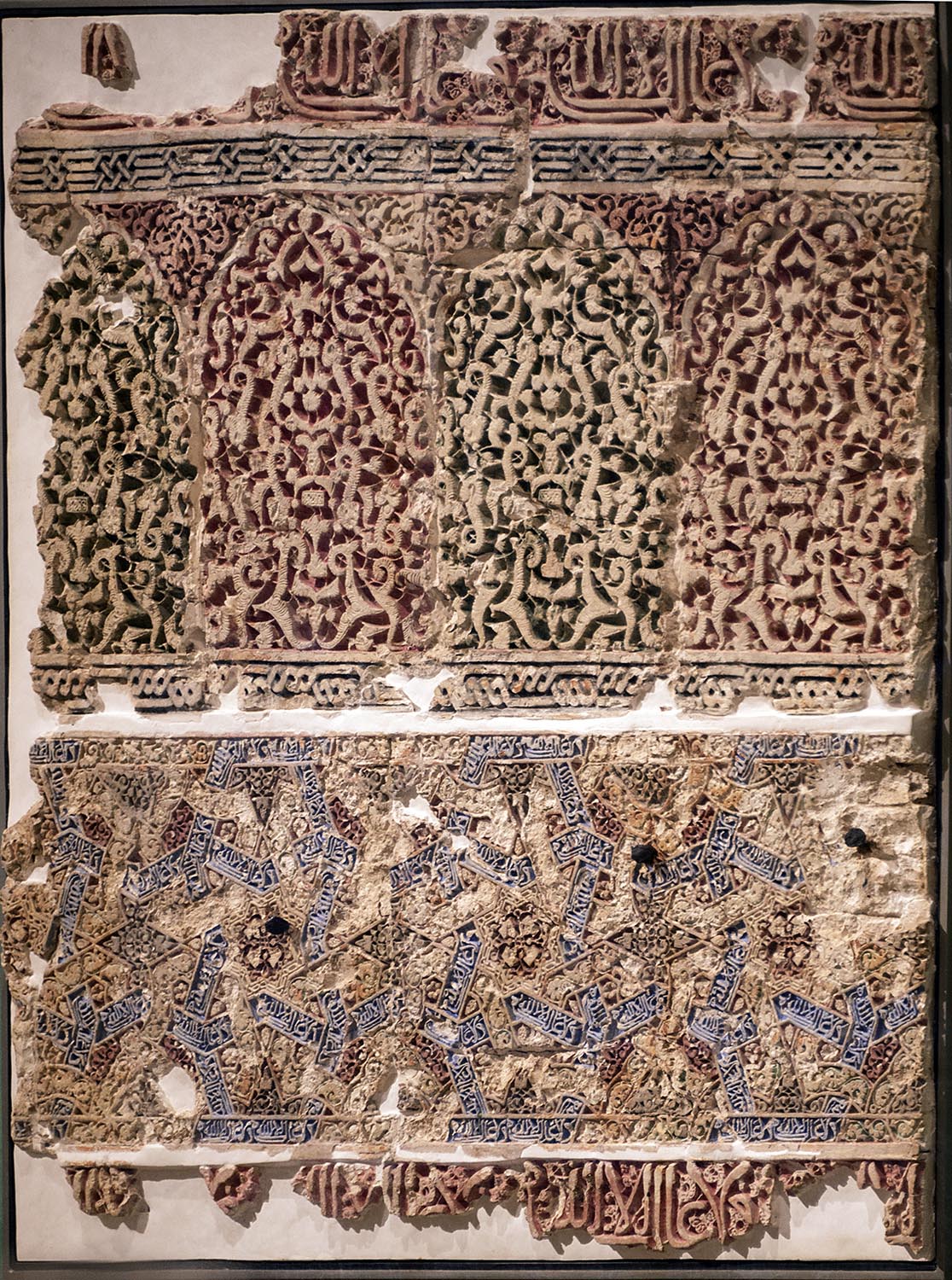 Polychromatic plasterwork panel with inscriptions on display at Alhambra Museum