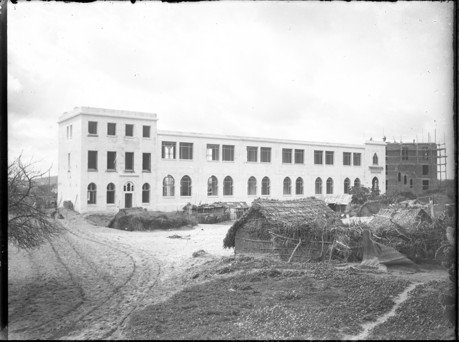 Lycée Regnault construction with straw huts in front 