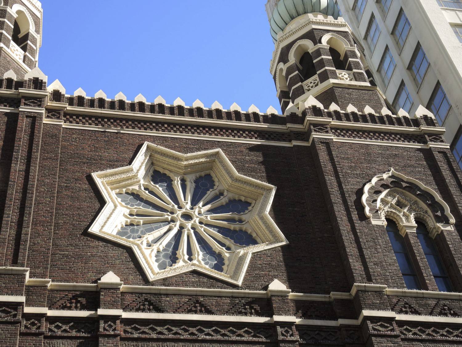 Exterior, detail view of the top portion of the façade, including the rose window, viewed toward the west tower on Baronne