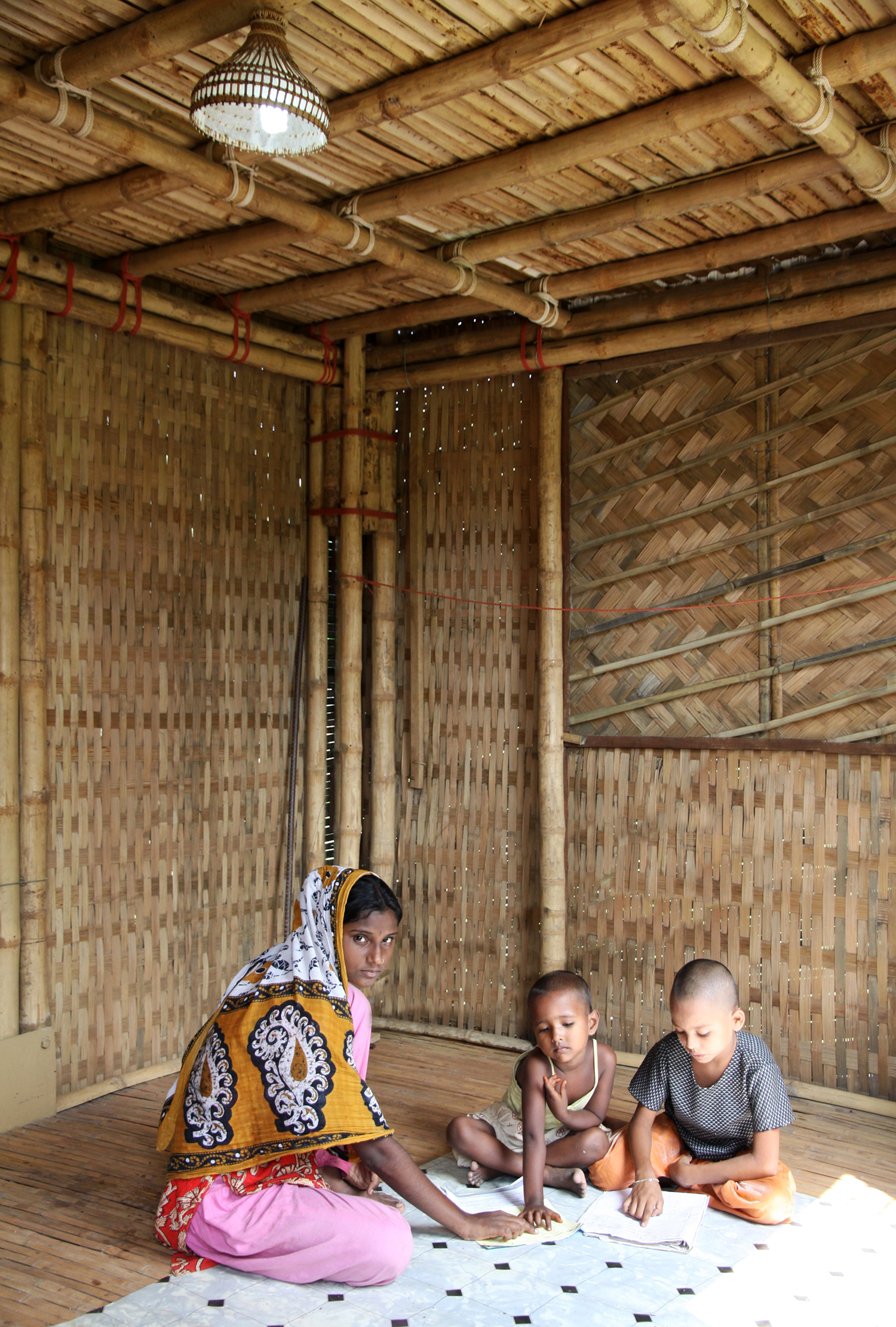Interior view of resident tutoring children in bamboo dwelling 