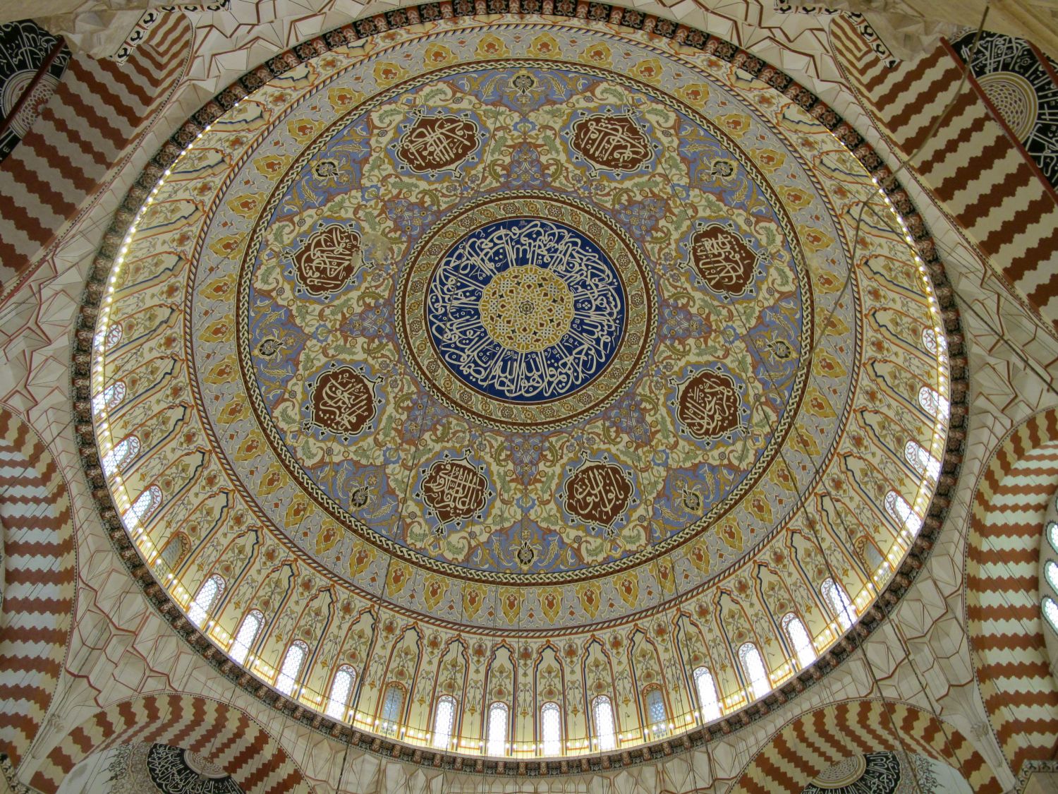 Interior view up at entire central dome, its surface decoration and part of the supporting vaults in alternating red and white stonework