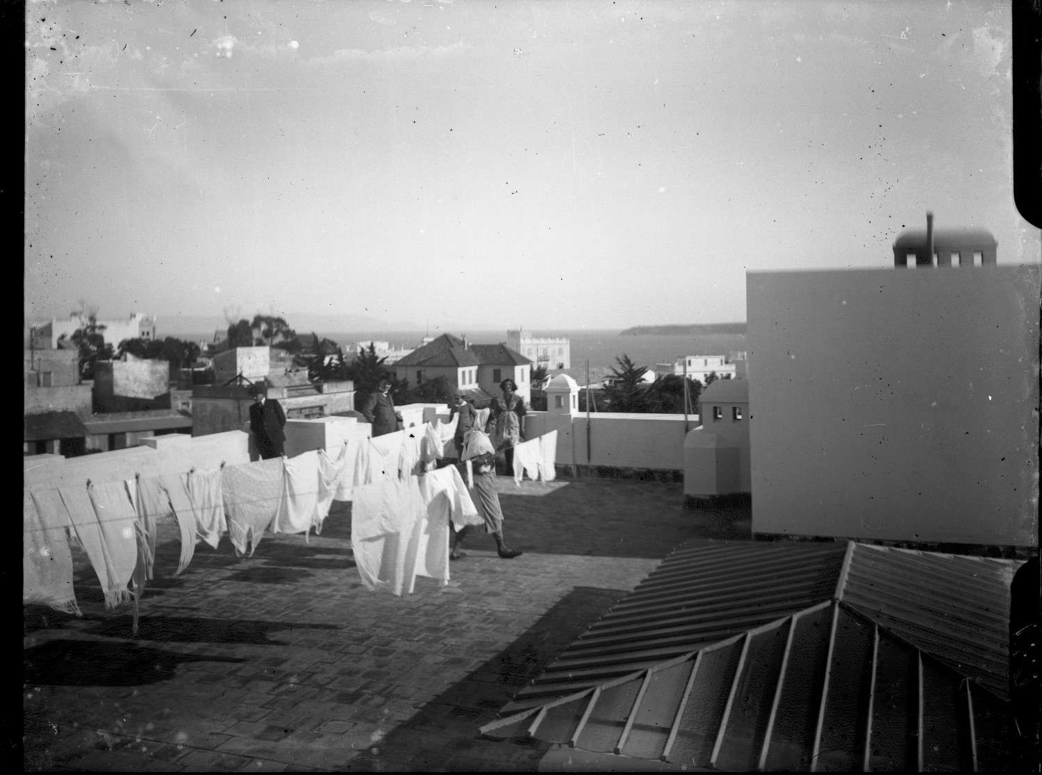 People with laundry on the roof at 65 rue Foucauld,  with a view of the Malabata and Spanish Coast in the background.
