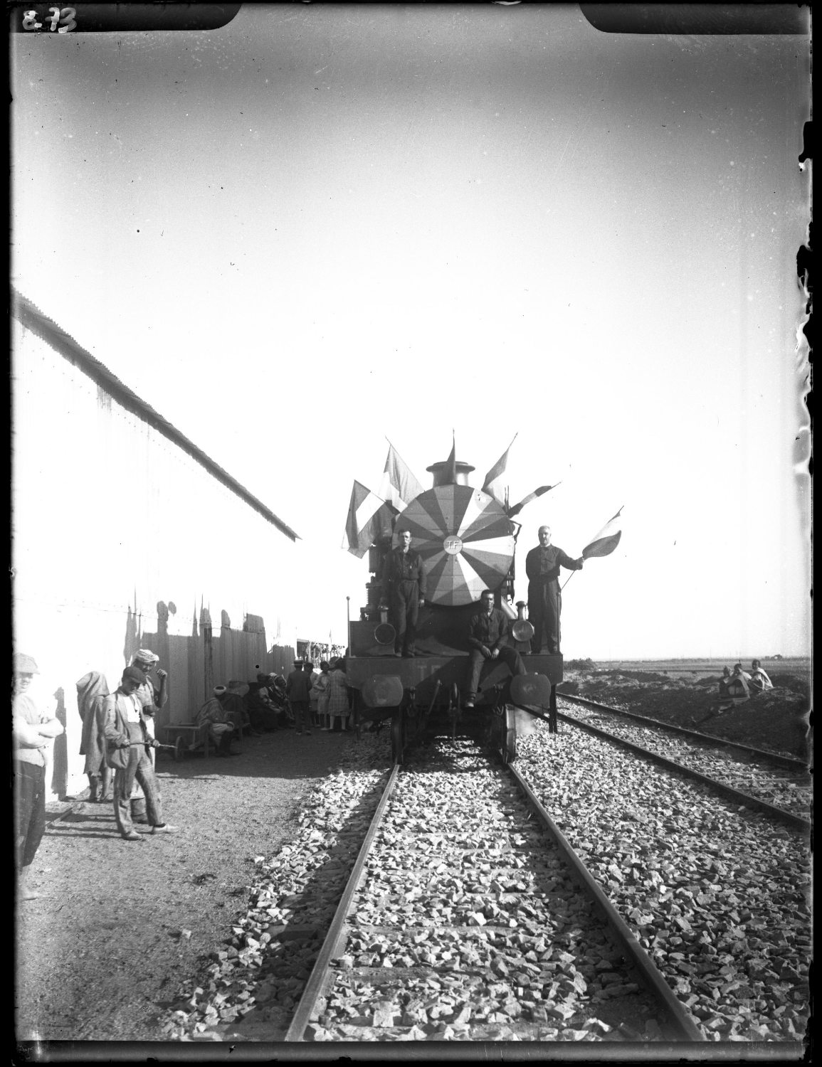 Front view, decorated front of the inaugural train at Tangier Charf station, crowd in European and Moroccan dress