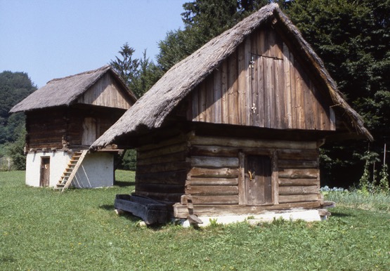 <p>These two single-cell granaries, along with those preceding and following, were relocated from farms in the Tuhinj Valley, to the east of Kamnik, to the open-air Ethnological Collection of the Medobčinski Muzej Kamnik, between 1968 and 1973. They vary in configuration but share similarities in materials and construction techniques. The granary in the foreground of this photograph dates from the 19th century, and incorporates a large roof volume with separate opening.</p>