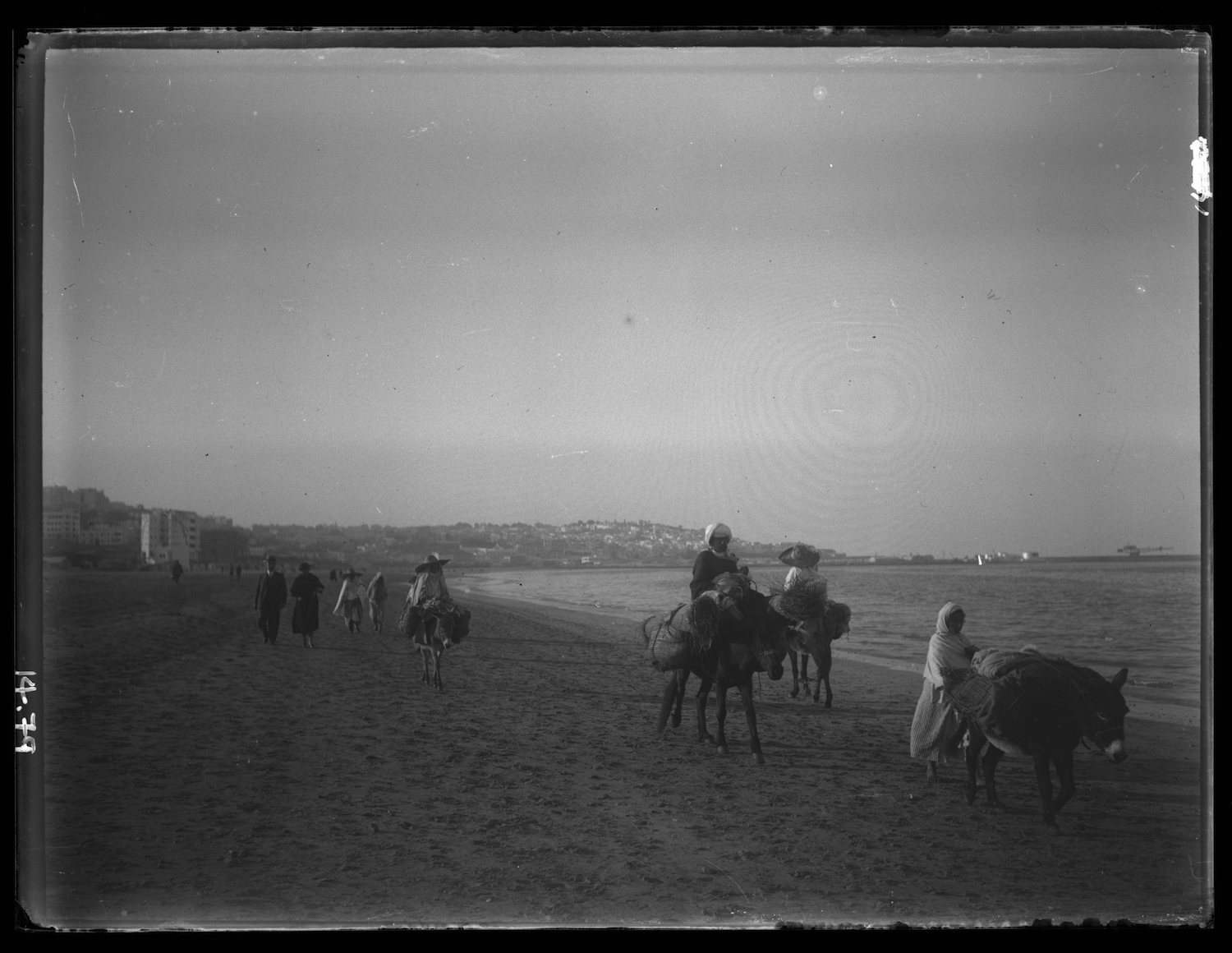 Beach front view of pedestrians and pack animals approaching from the medina 
