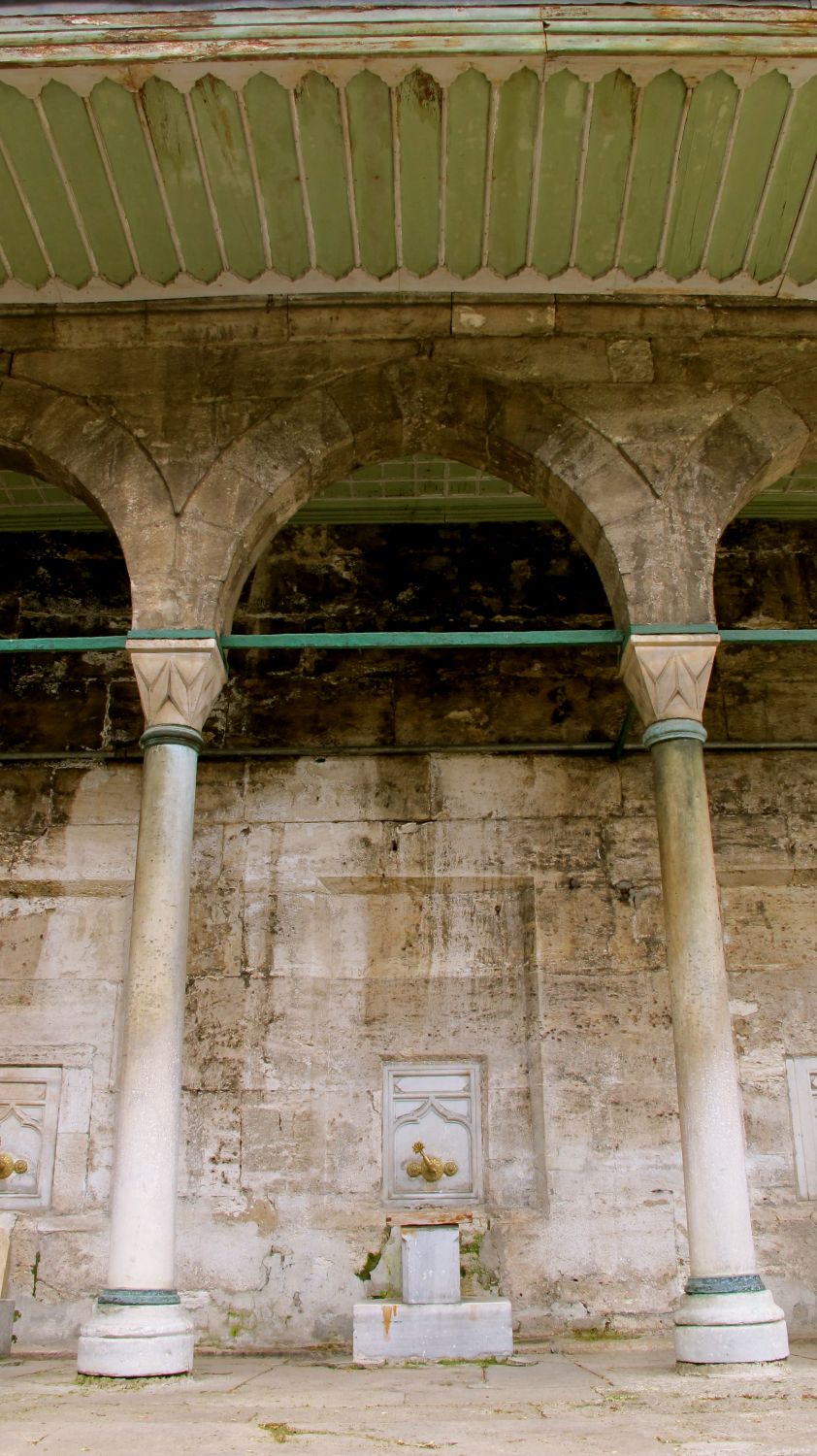 Detail view, one bay with ablution tap along colonnade wall of courtyard