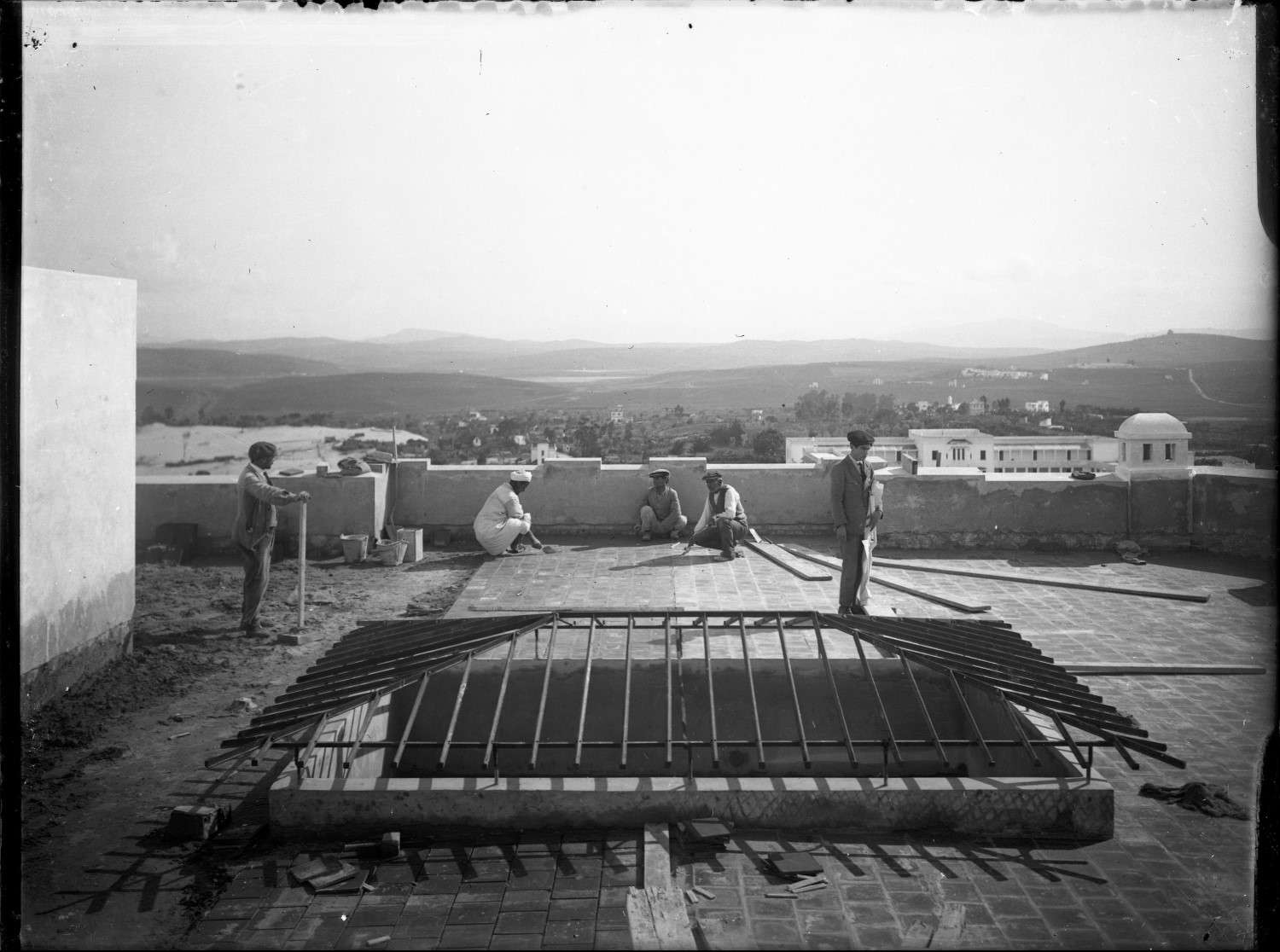 Construction on roof of 65 rue Foucauld, with mountains in background and workers in view.