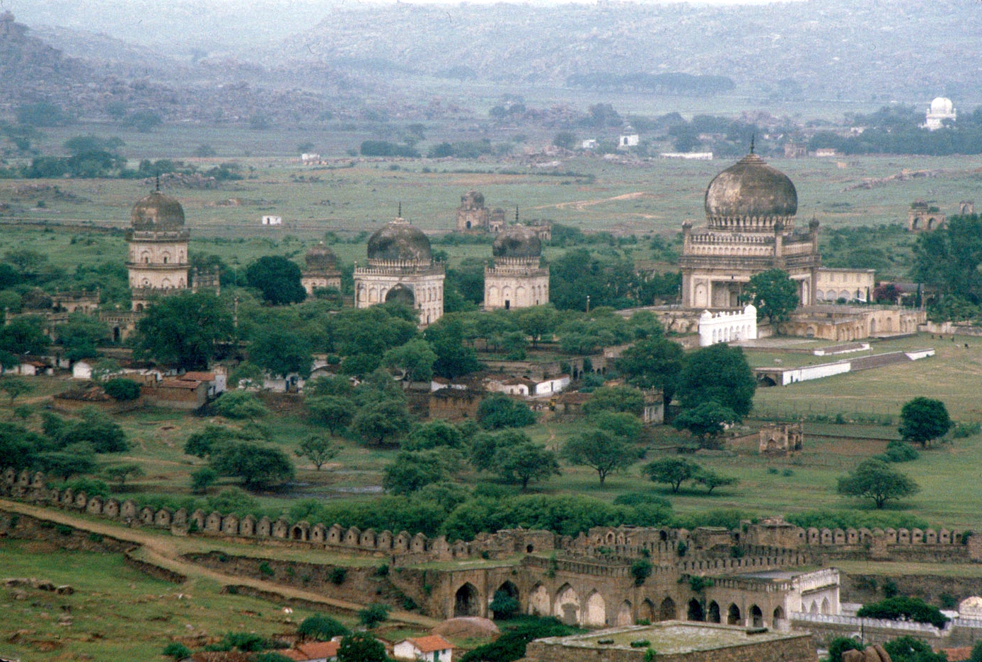 Qutb Shahi Royal Tombs - View of Golconda Fort wall in foreground, tombs in distance