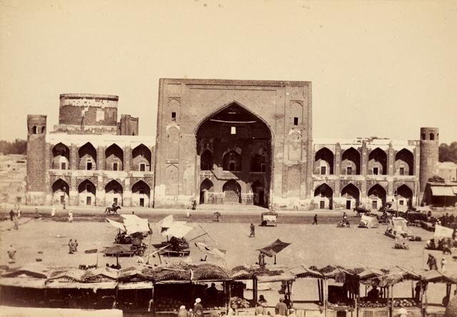 Exterior view from Registan Square showing the entrance iwan flanked by four bays of two-storied arched niches. The drum of the sanctuary (mosque) is visible on the left