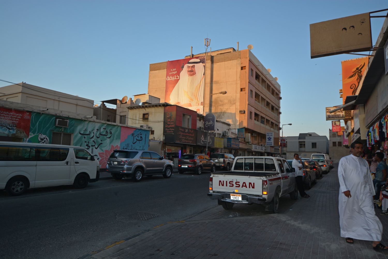 Street view with local businesses and pedestrians in Muharraq.