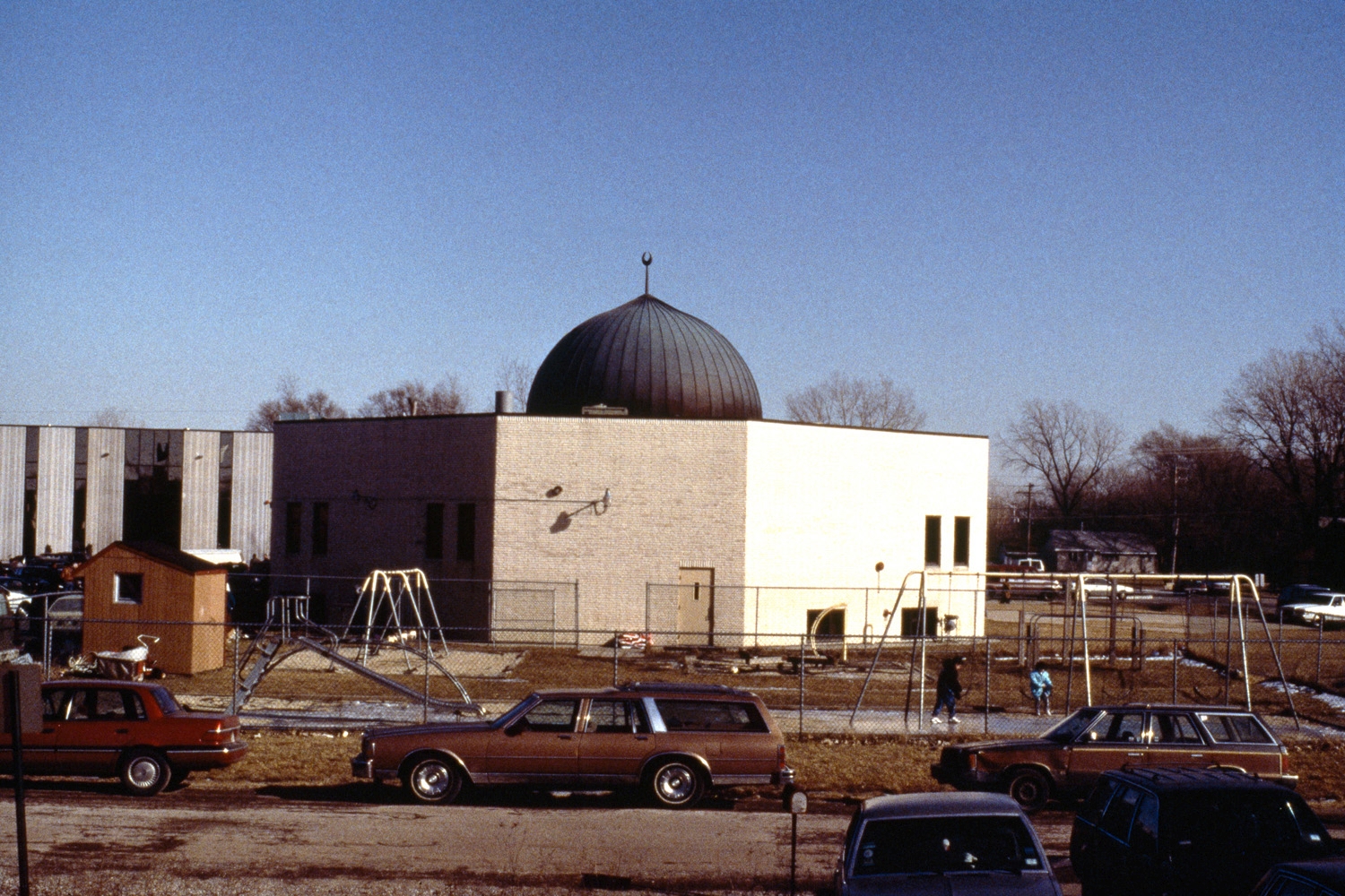 Exterior, view with playground in foreground; mosque prior to expansion