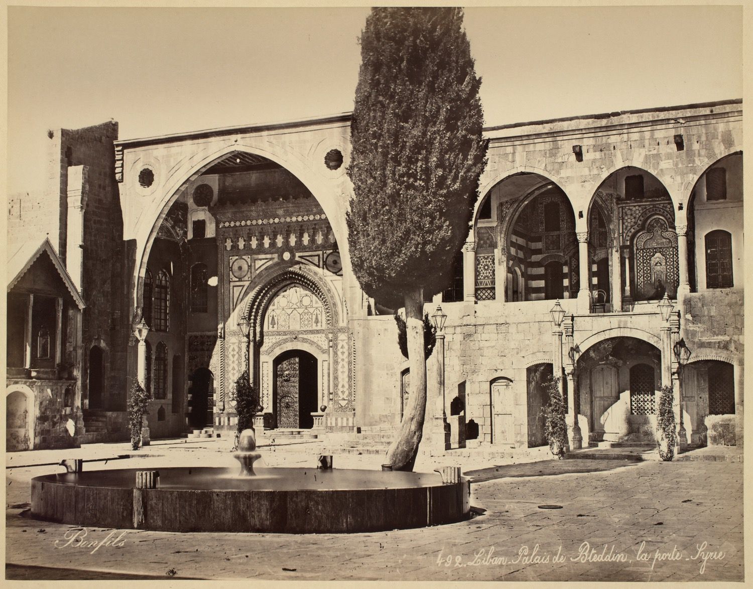 View of palace entrance with fountain and cypress tree in front