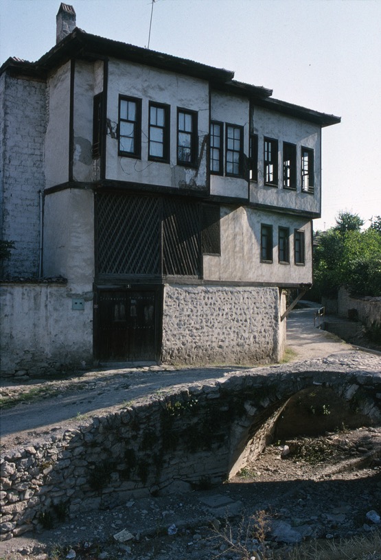 <p>The Taşatarlar şehir (town) house is located in the Babasultan mahalla along the Akçasu stream. The stepping uppermost level faces south. The ground level is formed with thick stone walls. The doors and latticework above conceal a two story hayat space within. The ground level interior also includes a stable, large oven and a stair to the open çardak and washing area that overlooks the hayat, and a separate kitchen, and living and sleeping room that faces the Dağdelen cami (mosque) to the north. The uppermost level contains a large corner çardak and three living and sleeping rooms.</p>