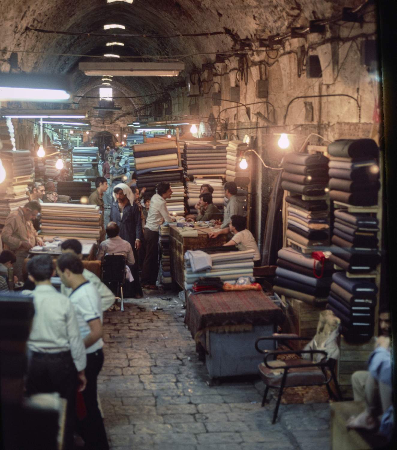 Fabric merchants along a vaulted market street.