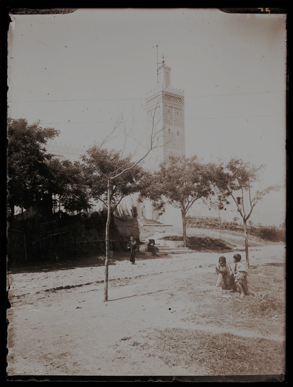 Distant view of the minaret from a field, children playing nearby