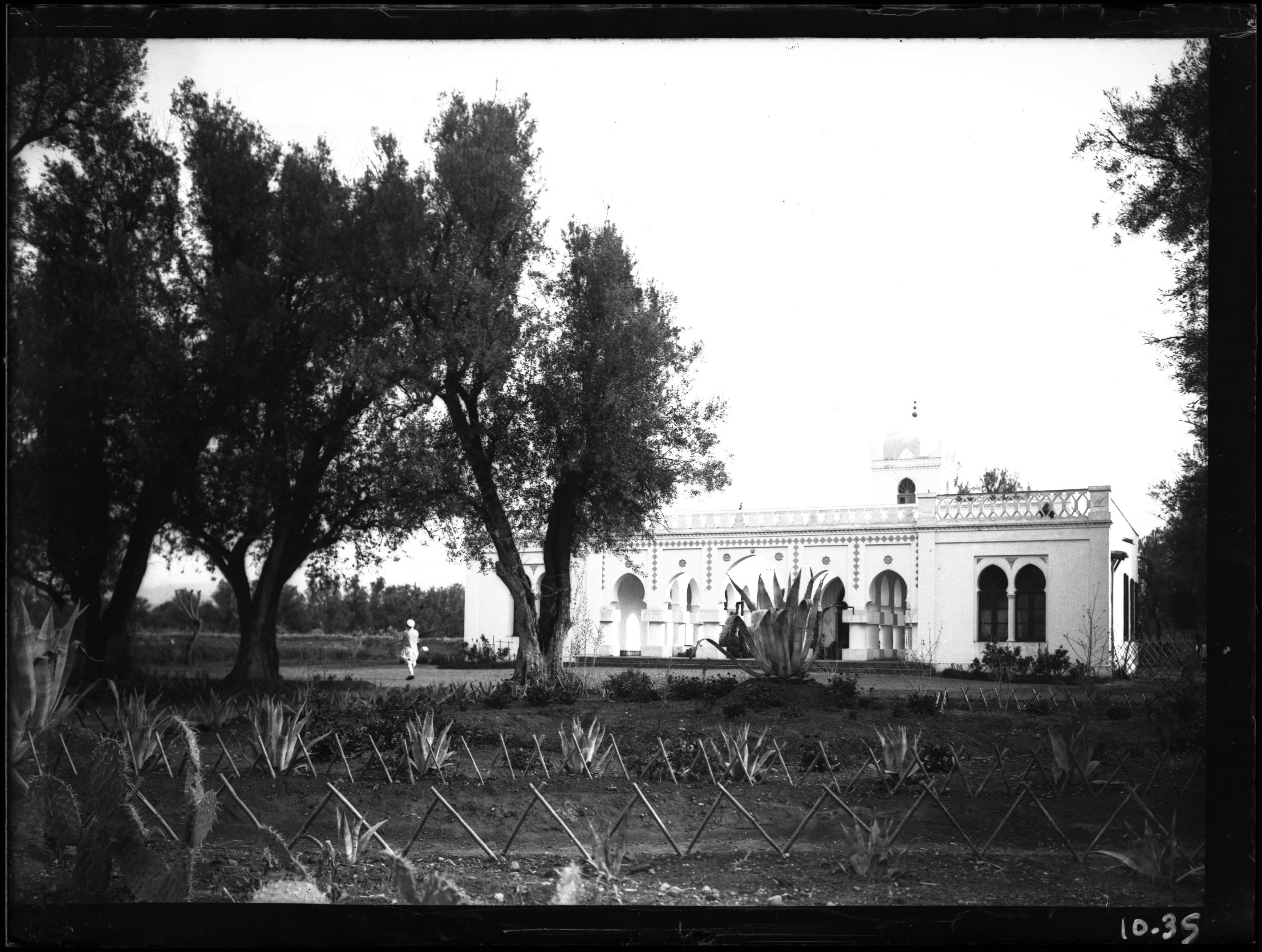 <p>Decorated building with large garden; man in Moroccan dress walking through</p>