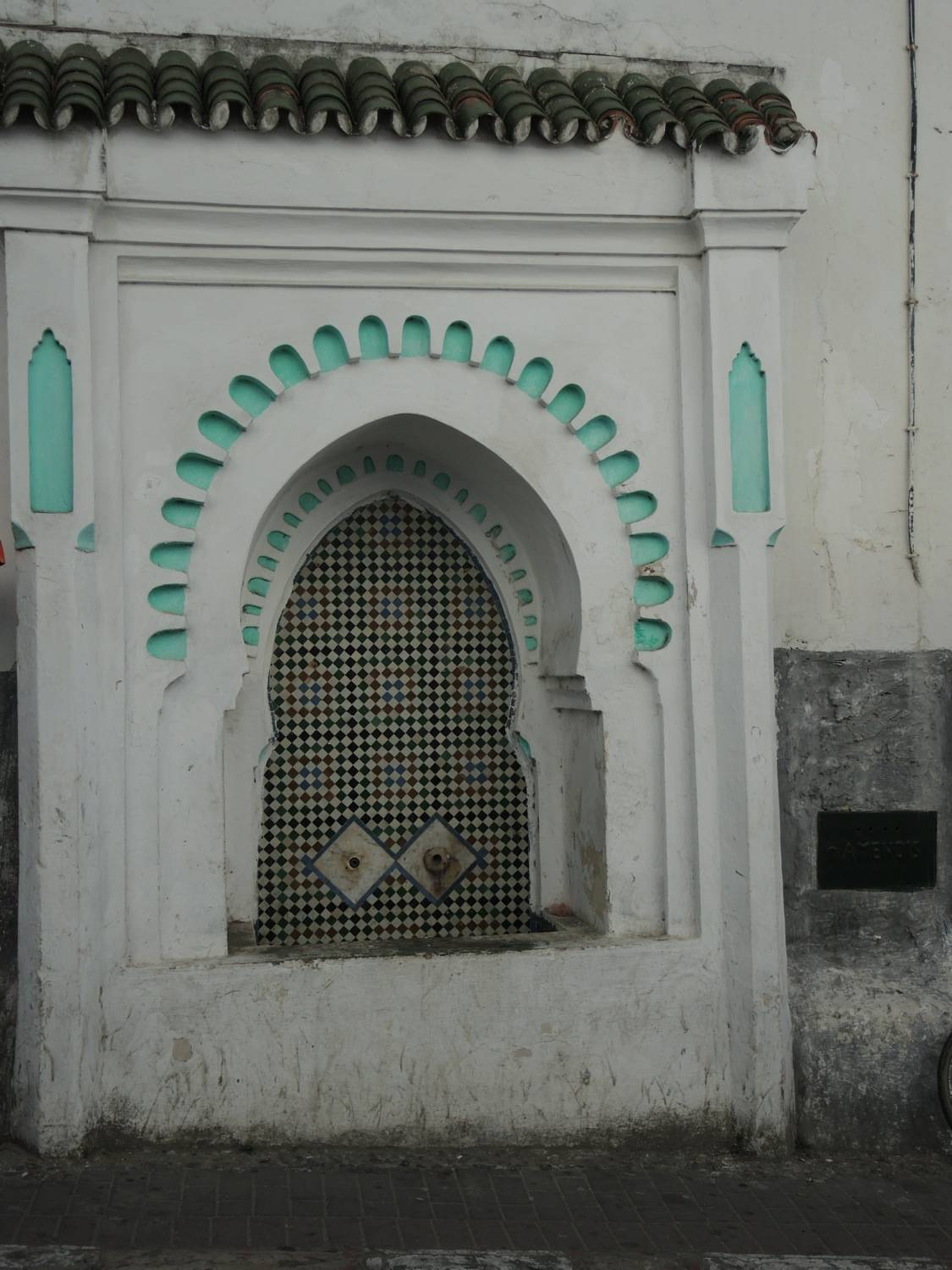 View of the fountain on the wall between the school and bathrooms, across the street from the mosque