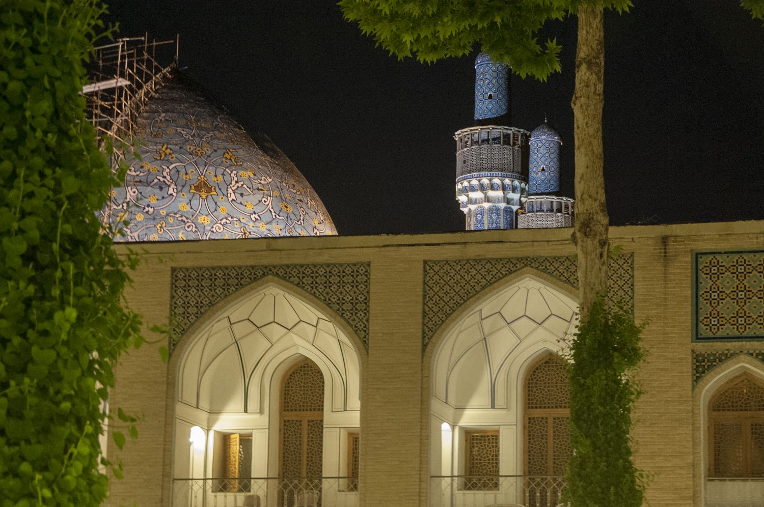Night view over southern facade of courtyard with dome and minarets of Madrasa-i Madar-i Shah visible in background.