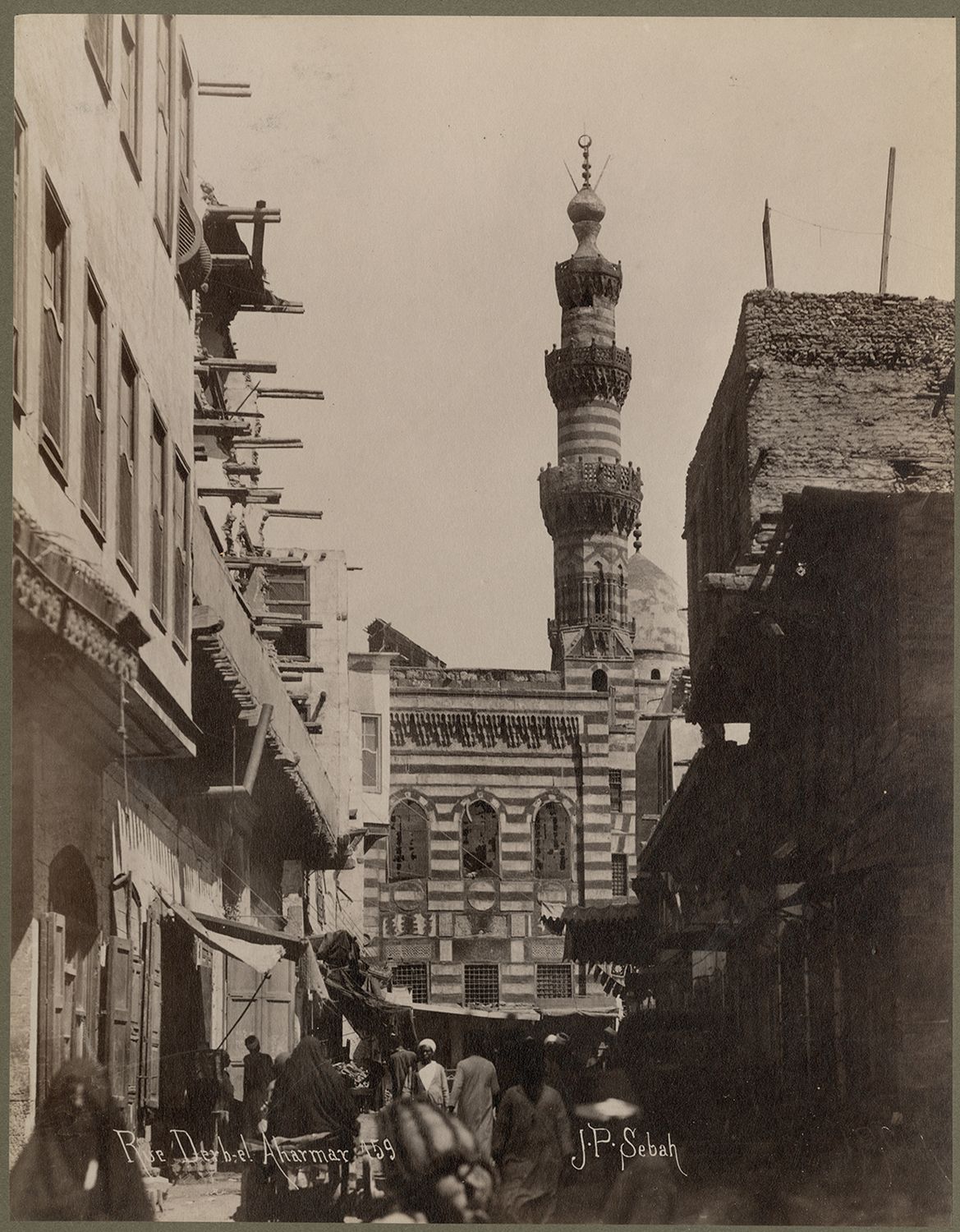 View along street in Darb al-Ahmar neighborhood, facing southeast. The ablaq facade of the Mosque of Amir Qijmas al-Ishaqi is visible at a bend in the street.