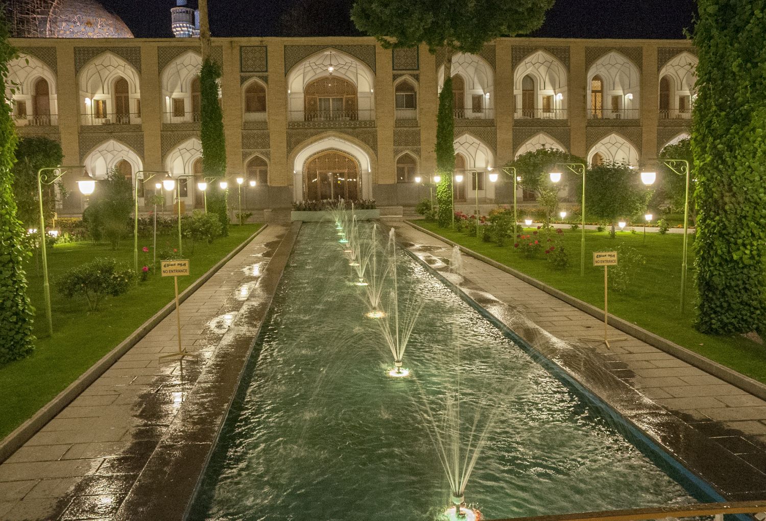 Night view of courtyard, looking south down central axis with water channel.