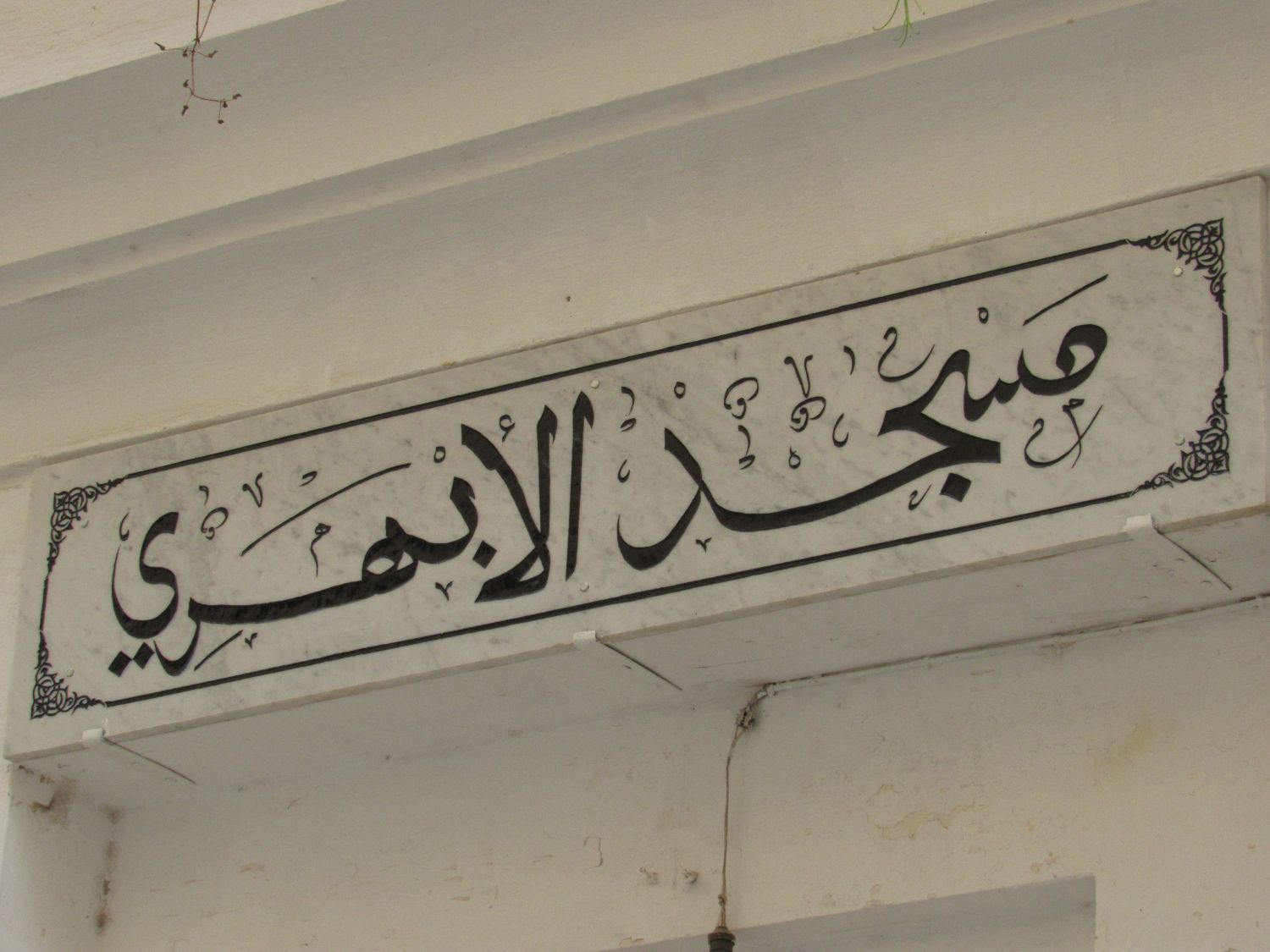 Exterior view, mosque name laid in stone above the entranceway.