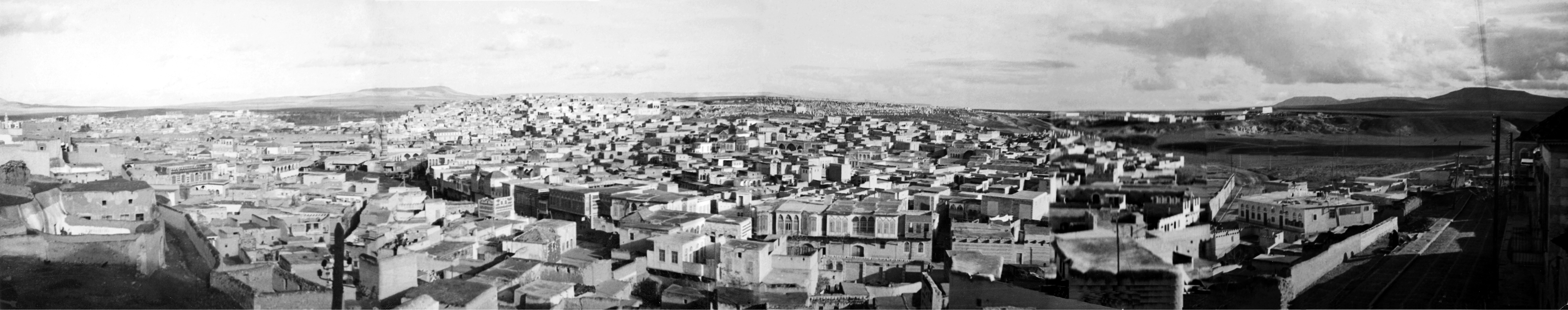 Hama - <p><strong>Hama - view of Al-Mahalba and Al-Hawarneh Areas</strong></p><p>This view of the southern part of old Hama city heads northeast and encompasses the Al-Mahalba and Al-Hawarneh areas. Prominent in the scene is Al-Jesser Street, with the standout Shishakli Palace featuring upper balconies and adorned windows. The distant view includes the al-Farraiya quarter and a cemetery.</p>